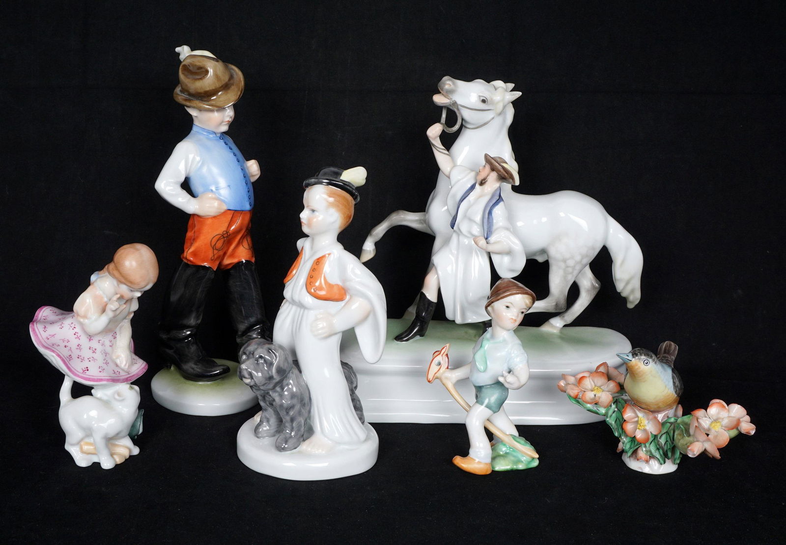 Six Herend Porcelain Figurines: Six pieces total, each with assorted incised numbers and blue Herend stamp marks, to include 1) Man with horse, 7.5" h. x 7.5" x 3.25". 2) German boy 8" h. 3) Girl with cat, 4.5" h. 4) Boy with dog 6.