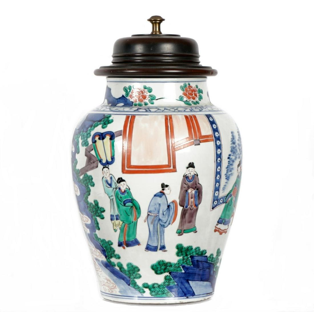 Chinese Famille Rose Covered Jar: Decorated with courtyard genres scene, turned wood lid, overall 17.5" h. x 10" dia. Condition: Base drilled. From the estate of a prominent lawyer from New Rochelle, NY.