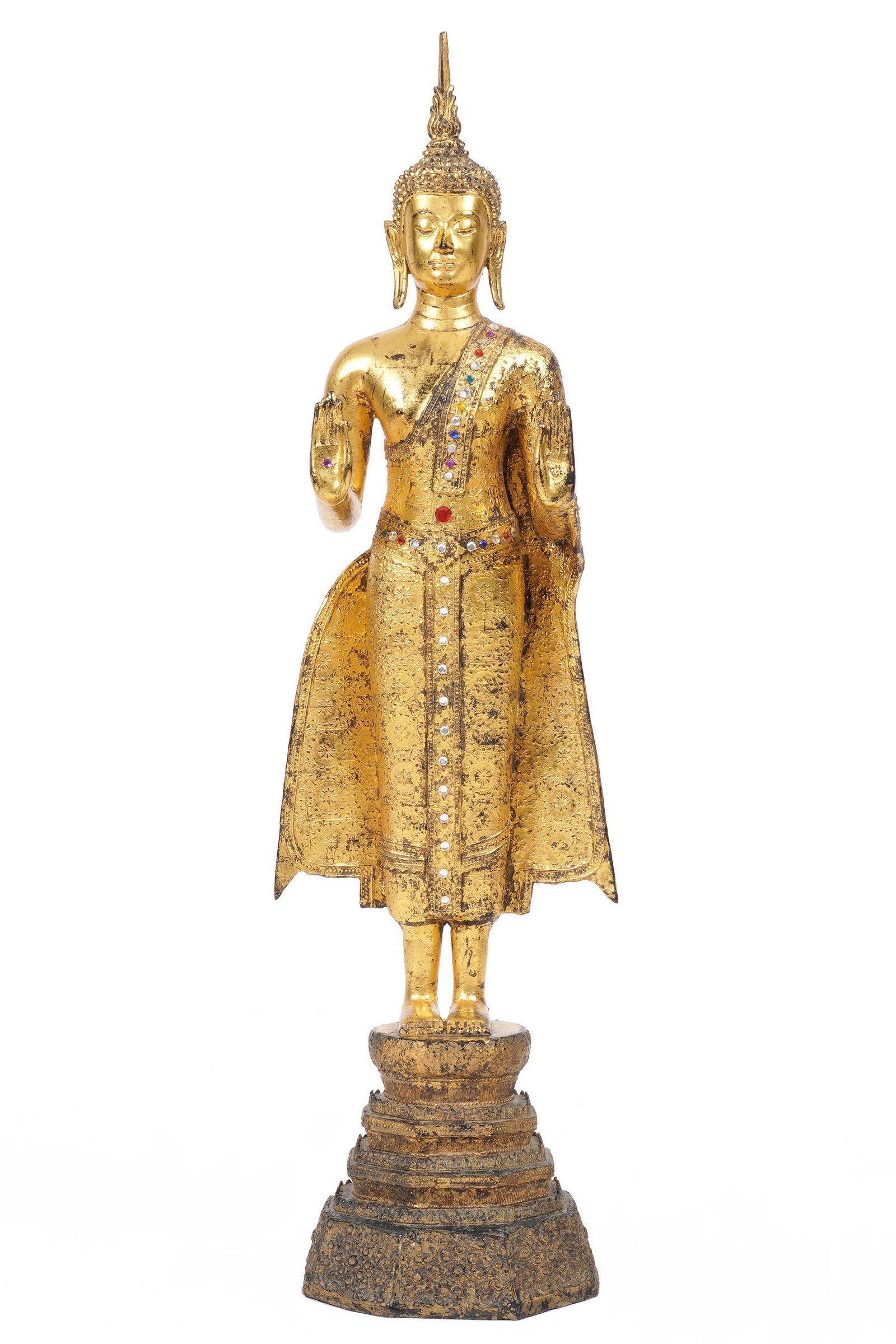 Bejeweled Gilt Bronze Standing Buddha: Gilt decorated bronze figure of a standing Buddha with applied glass "jewels", overall measures 36.75" x 10.5". Condition: Loss of gilt. From the estate of a prominent lawyer from New Rochelle, NY.