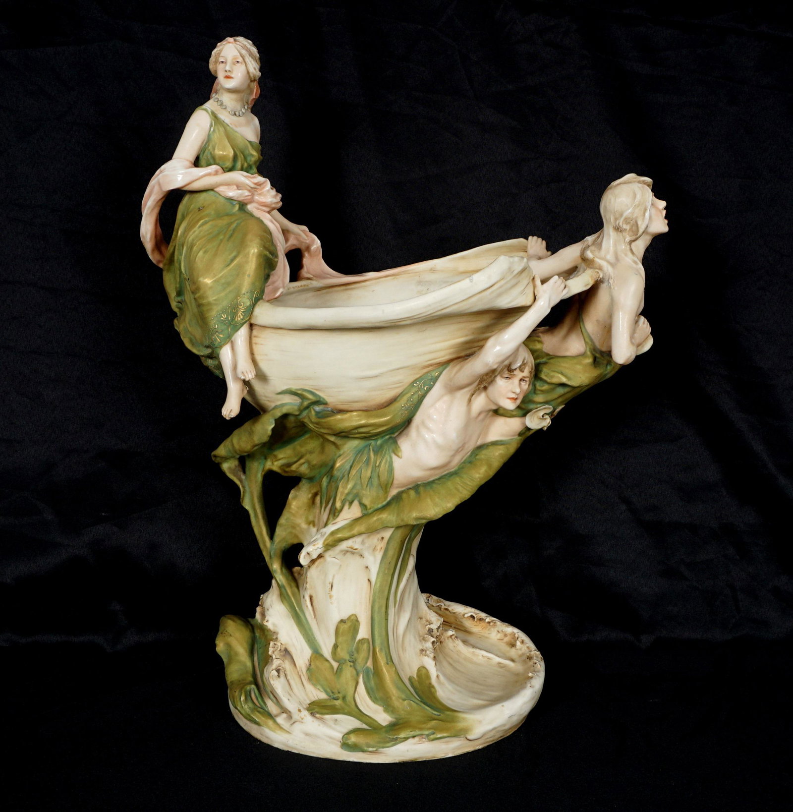 Royal Dux Porcelain Figural Centerpiece: Large centerpiece with three figures and foliate motifs, well marked under foot, overall 23.75" h. x 19" x 11.25". Condition: Repairs to one maiden arm, cracks and repair to base, chips. From the esta