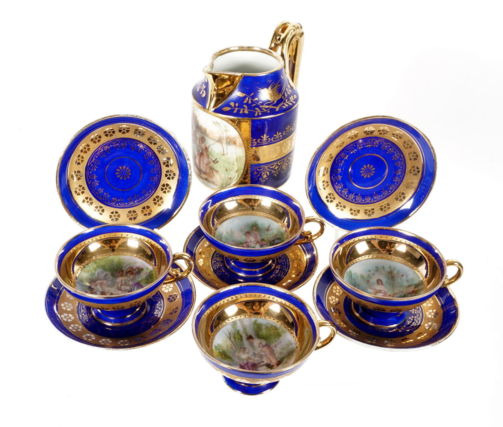 Ten Piece Royal Vienna Demitasse Set: Hand painted with cobalt and gilt ground, hand painted genre scenes in reserves, to include pitcher (5" h. x 4.25"), four cups 1.75" h. x 3.5", five saucers 4" dia. From the estate of a prominent lawy