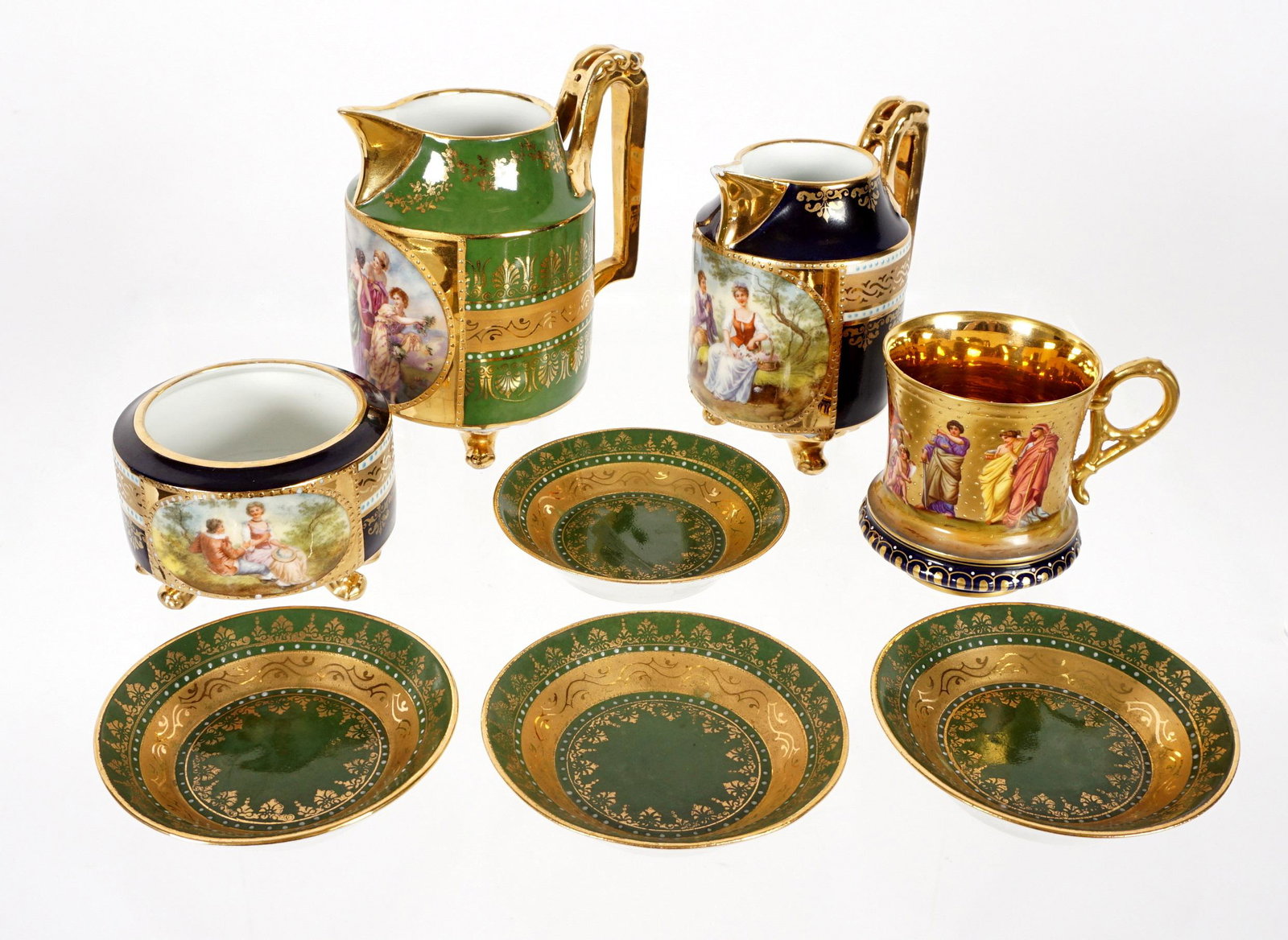 Eight Piece Collection of Royal Vienna Porcelain: an assembled collection of eight pieces total to include 2 pitchers, gilt ground cup, four demitasse saucers, and an open bowl. Largest pitcher measures 5" h. x 4.5". Condition: Smallest pitcher has c