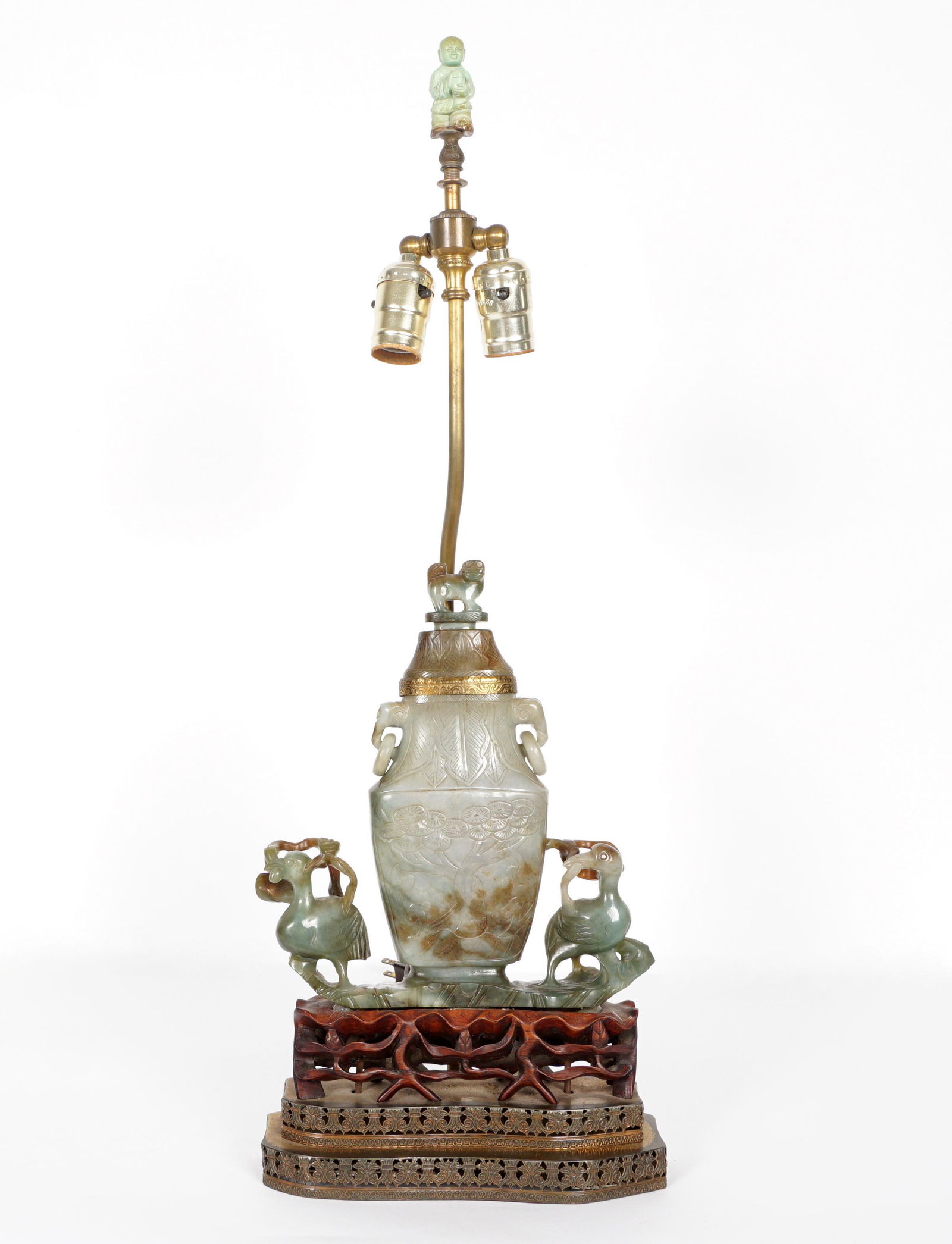 Antique Large Chinese Carved Jade Urn and Birds Lamp: Center carved mottled celadon jade or similar stone covered urn with foo dog finial, ring handles. Flanked on either side with figural birds, on pierced carved wood plinth over reticulated brass stepp
