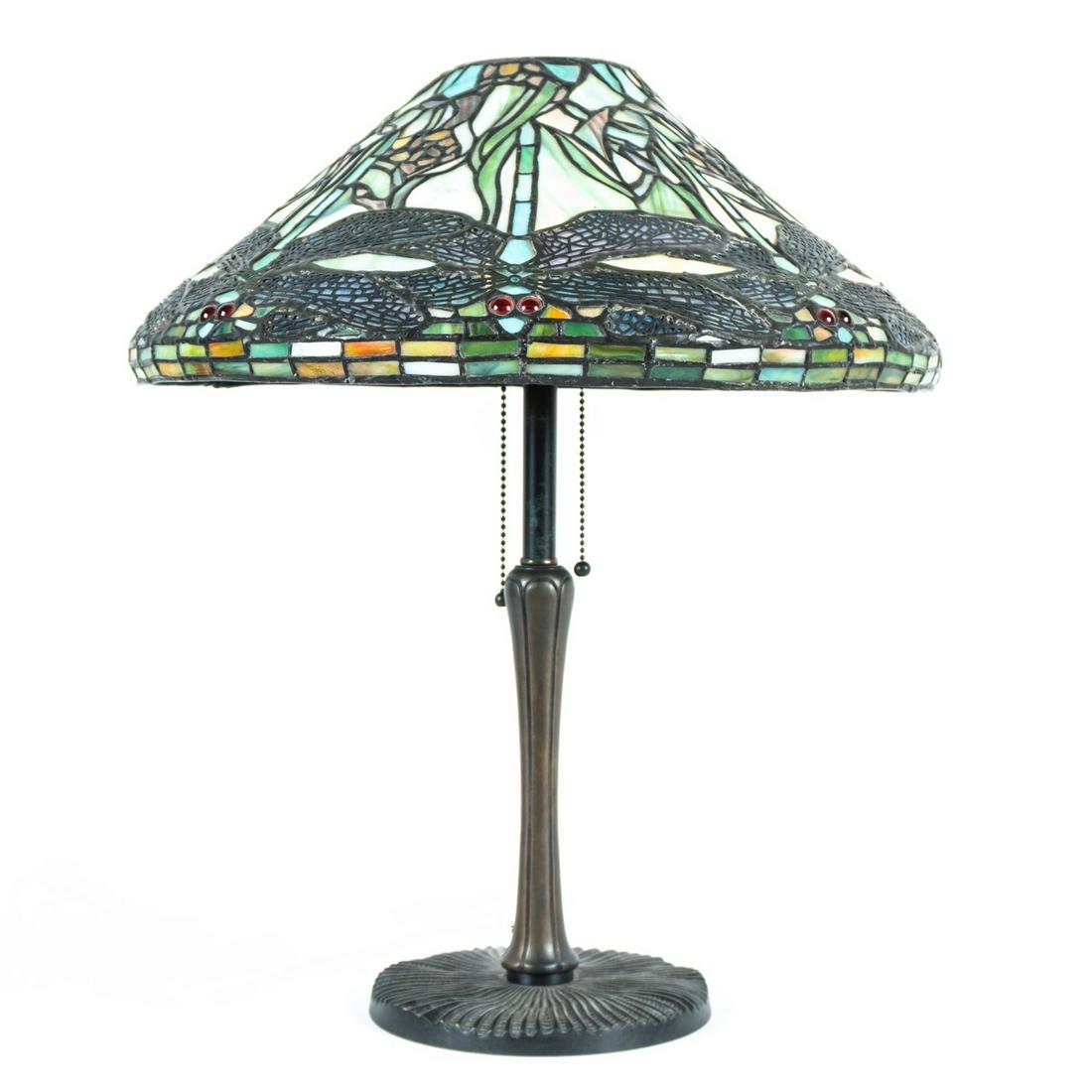Tiffany Style Dragonfly Leaded Glass Lamp: Dragonfly motif leaded glass shade with red jeweled eyes, bronze base with ribbed foot, double socket fixture, missing heat cap. Base measures 20.5" h. x 7.5" dia. From the estate of a prominent lawye