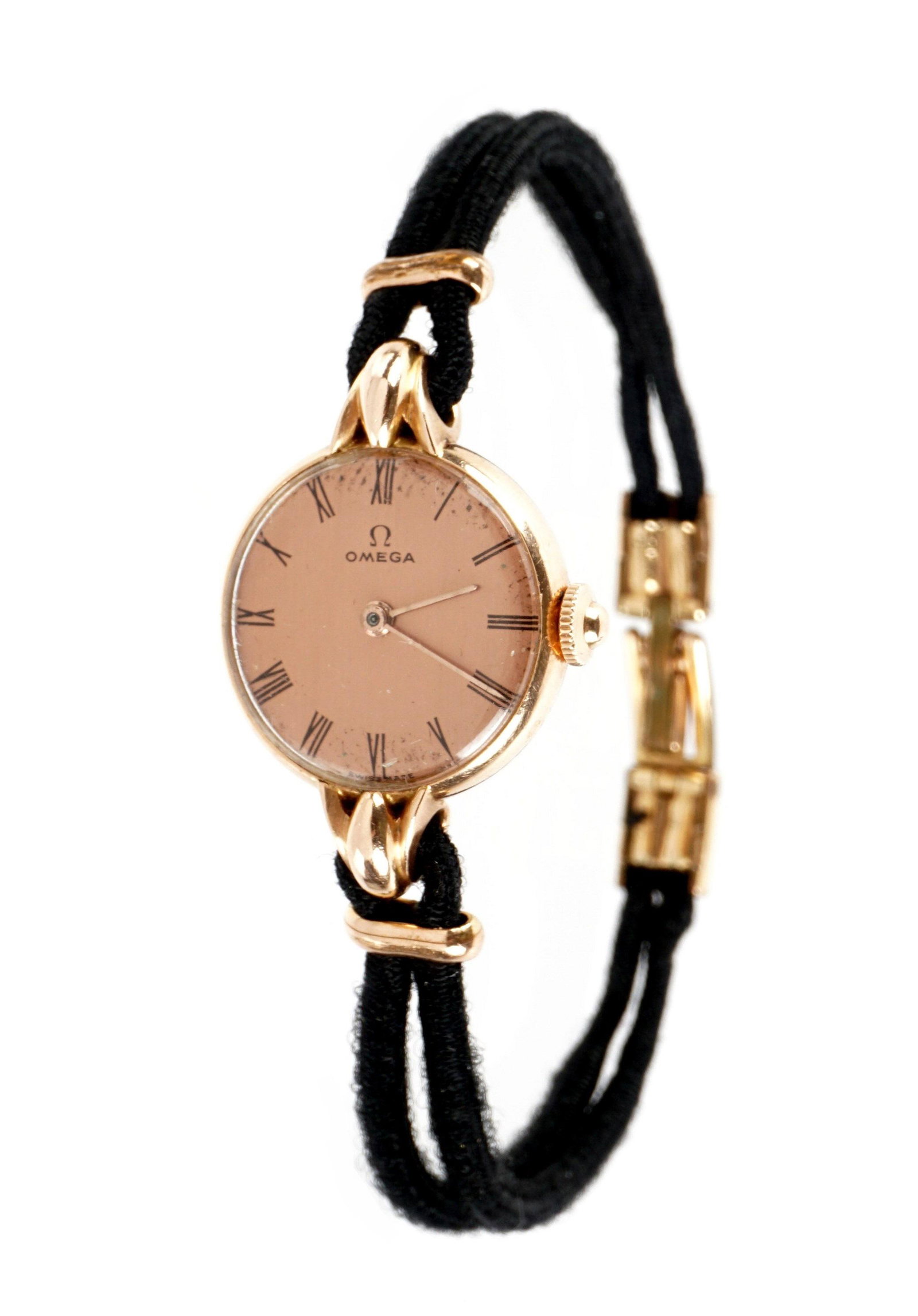 Ladies 14k Gold Omega Wrist Watch: 14k gold case, rose colored dial marked Omega, case approx. 20mm dia. Hand wound movement. Corded bracelet with 14k gold clasp, overall 7.25" long. Currently running however not guaranteed to continue