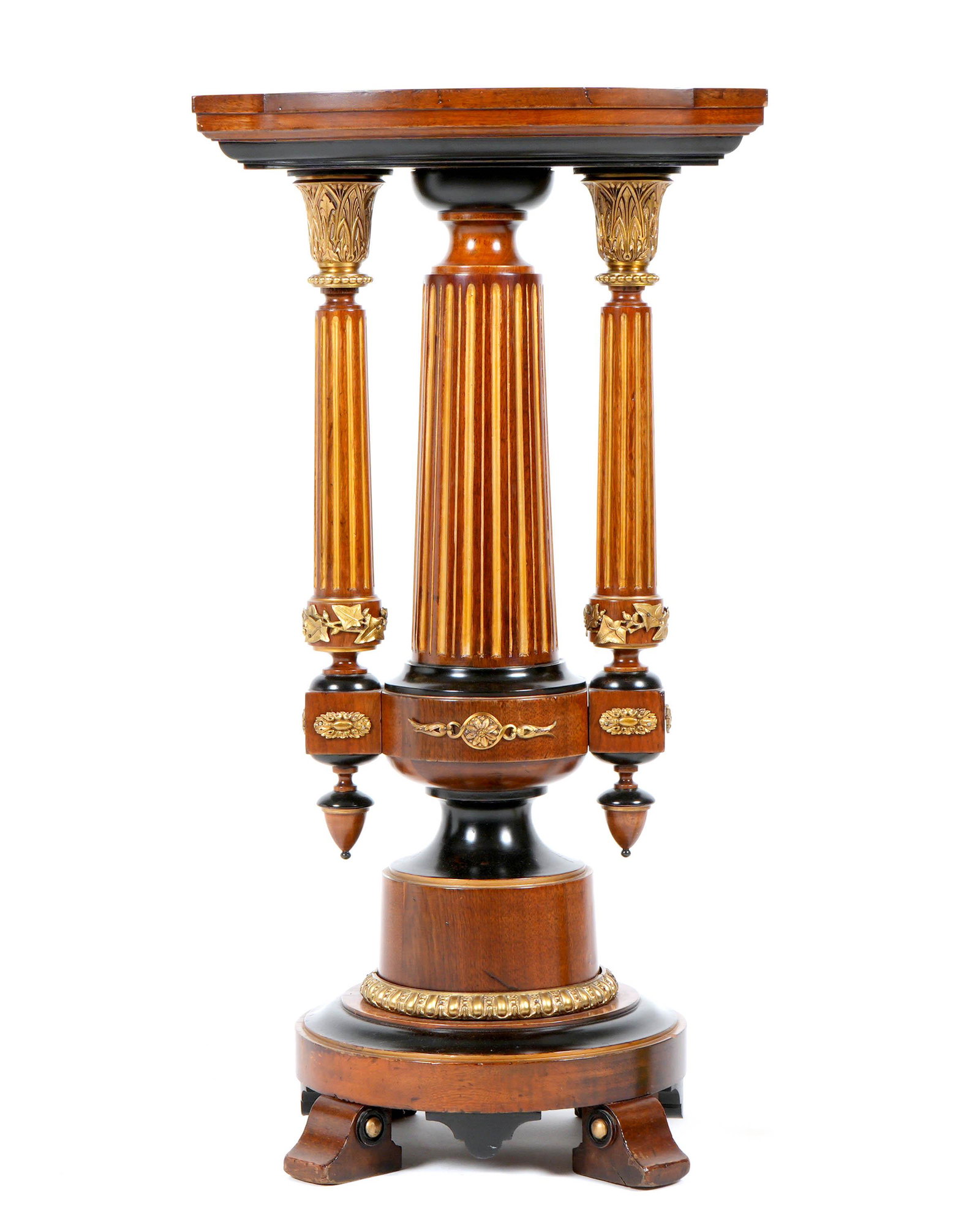 Victorian Mahogany and Gilt Bronze Pedestal: Serpentine top over fluted center support, two side supports with gilt bronze mounts and applied decoration. Turned ebonized and mahogany base, gilt bronze decorations, all on four feet. Overall 38.5"