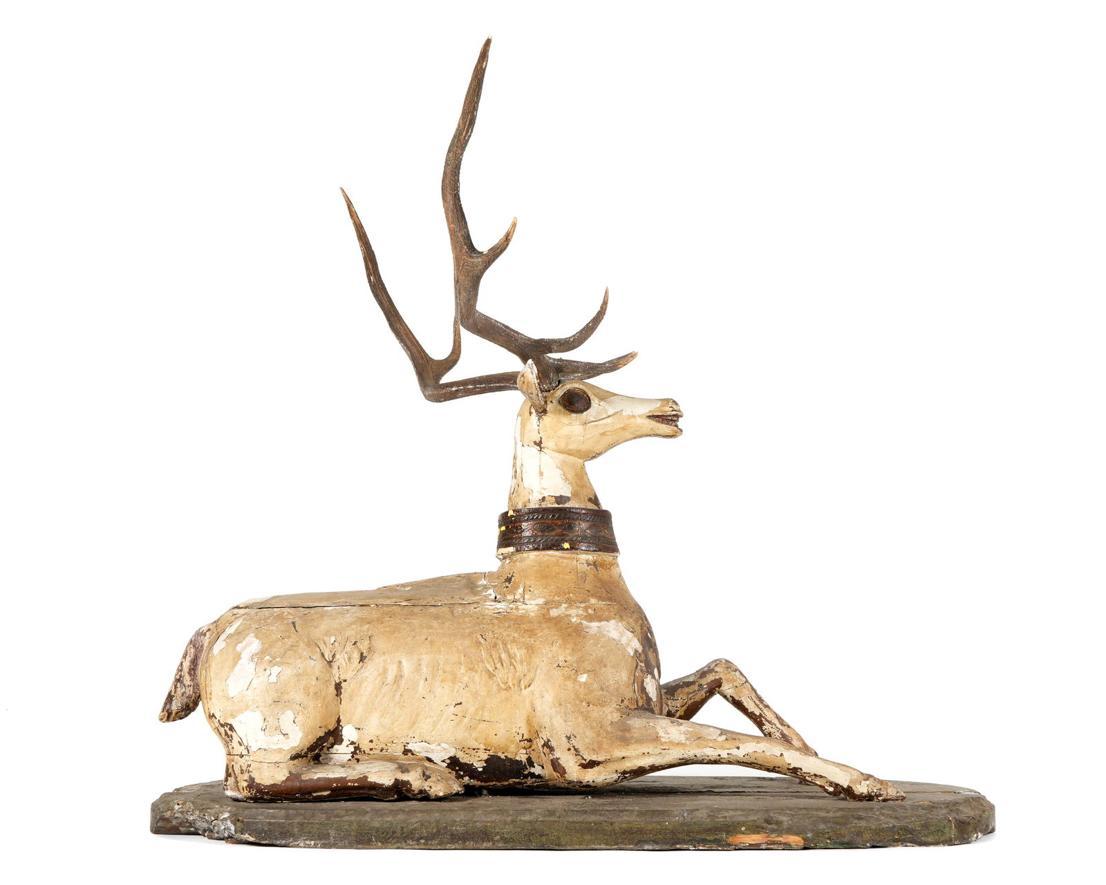 Life Size Carved Polychrome Deer ex Tony Duquette: Carved and polychrome paint decorated figure of a recumbent deer, removable composite antlers, on green painted oval base. Previously part of a pair owned by the designer Michael Taylor, one acquired