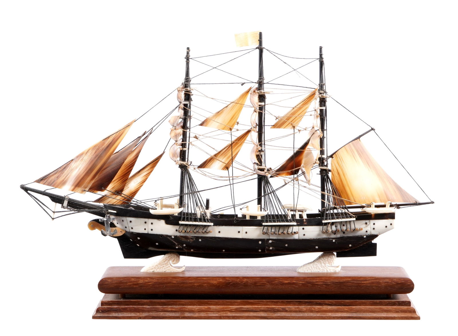 Baleen and Whale Bone Clipper Ship Model: Model of a clipper ship with three masts, horn sails, rigging, and six life boats. Overall measures 9.5" h. x 18" x 4". Sold with wood stand with crashing wave mounts. 2.75" h. x 14" x 4.5". Condition