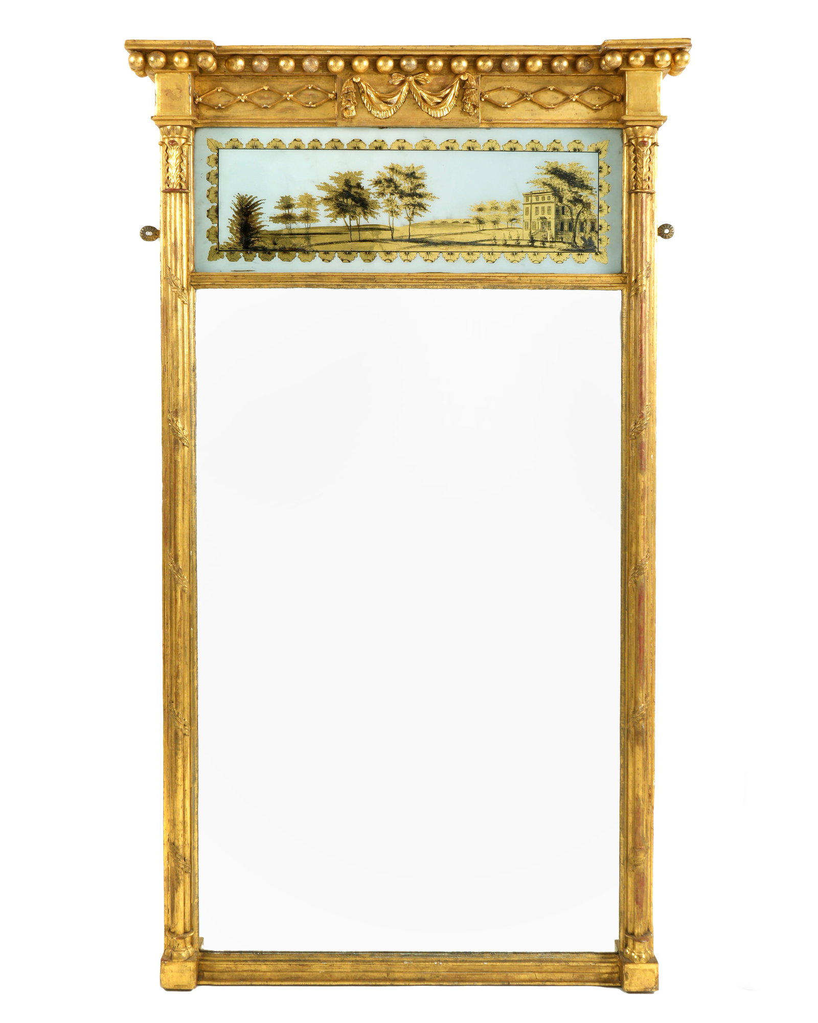 American Federal Carved Giltwood Eglomise Mirror: Carved and molded cornice with spherules and tapestry swag. Eglomise panel depicting landscape with house over mirror. Fluted half column sides. Overall 50.75" h. x 29". Condition: Wear to gilt, very