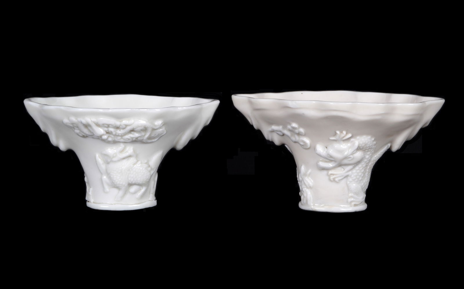 Two 17th/18th Century Chinese Dehua Blanc de Chine Libation Cups: Two piece total, porcelain white blanc de chine glaze horn form. To include 1) Scalloped top rim, raised dragons and clouds motif, 3.25" h. x 5.75" x 4.25". 2) Scalloped rim, raised qilin and other de