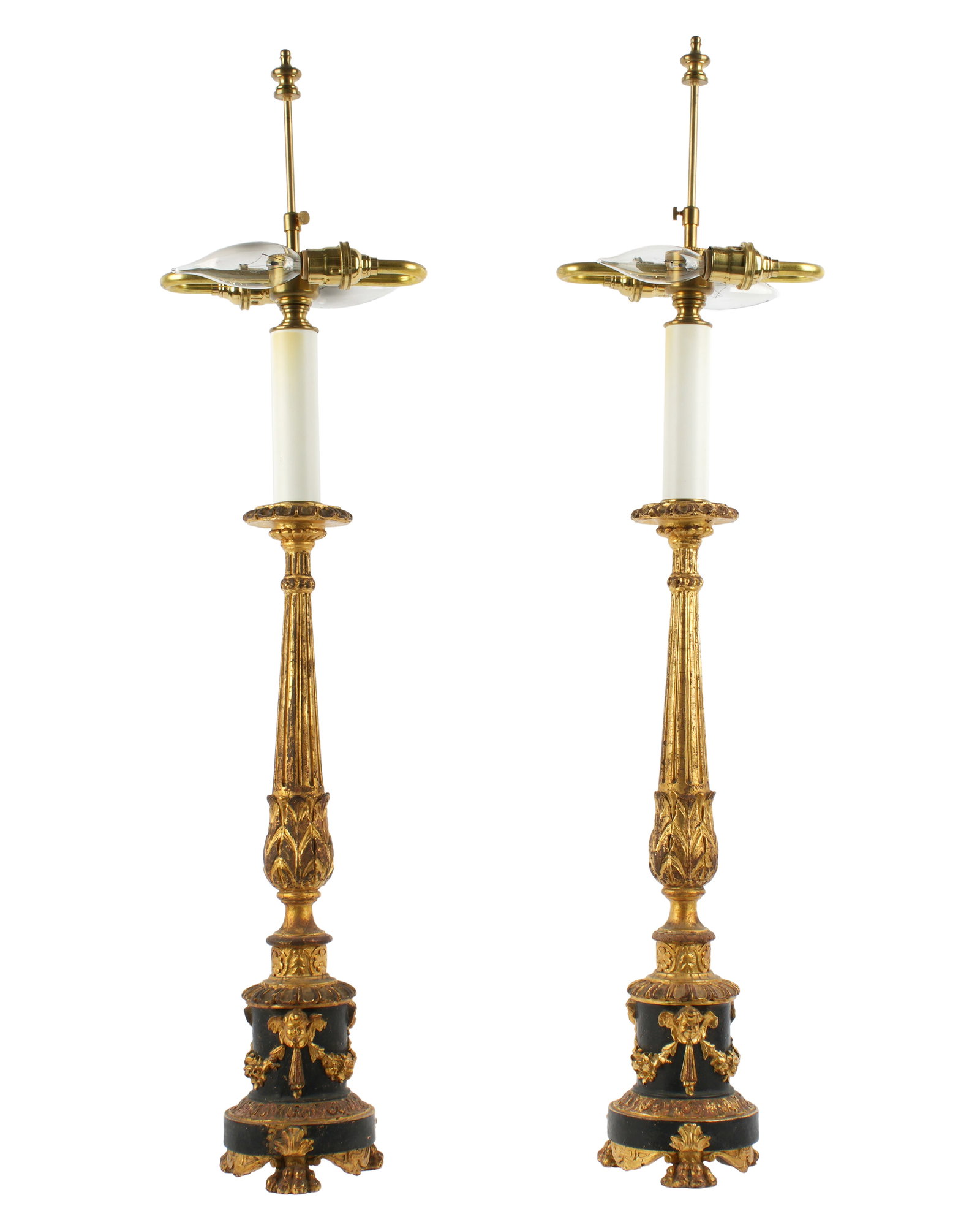 Pair French Carved Parcel Gilt Candlestick Lamps: Carved gilt and ebonized wood candlestick form lamps. Fluted column shaft over round base with figural cherub masks and swags, all on three paw feet. Double socket fixture. Overall 30.5" h. x 4.25". C