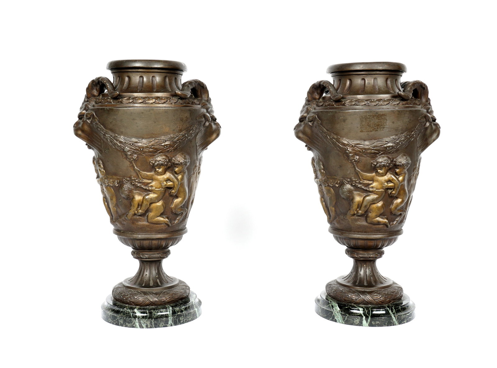 Pair Patinated Spelter Neoclassical Urns: Matched pair spelter urns with neoclassical motifs, figural mythological horned creator handles, putti at play on body, green variegated marble bases, overall 14.75" h. x 8.5". Dings, cracks, and hole