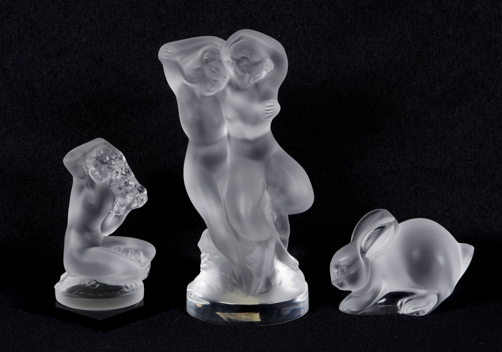 Three Lalique Frosted Crystal Figures: Three pieces total from Lalique to include 1) "Floreal" nude woman fixing her hair, 3.5" h. x 2" x 2". Original box, 2.5" x 5.5" x 5.5". 2) "Le Faune", dancing nude women, 5.5" h. x 2.5" x 2". Incorre