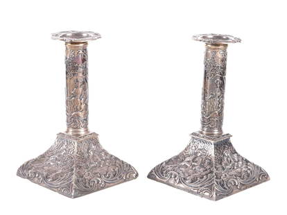 Pair William Comyns & Sons Silver Candlesticks: Pair embossed weighted English silver single light candlesticks, round shafts with ladies and musician in courtyard, base with four panels depicting resting shepherd and dog. Hallmarked William Comyns