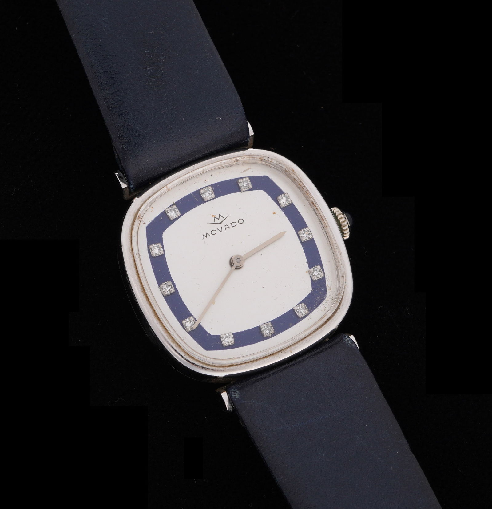 14k Gold and Diamond Movado Ladies Wrist Watch: Ladies Movado manual wind wrist watch, 27mm 14k white gold case, bushed metal and enamel dial with accent diamond markers, blue leather band, 8.5". Condition: Minor spotting to dial, minor signs of we