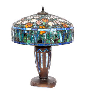 Tiffany Style Mosaic Leaded Glass Lamp: Heavy cast bronze base with glass mosaic inserts, unsigned. Floral motif leaded and stained glass shade. Base measures 24.25" h. x 8.25", shade 8" x 19".