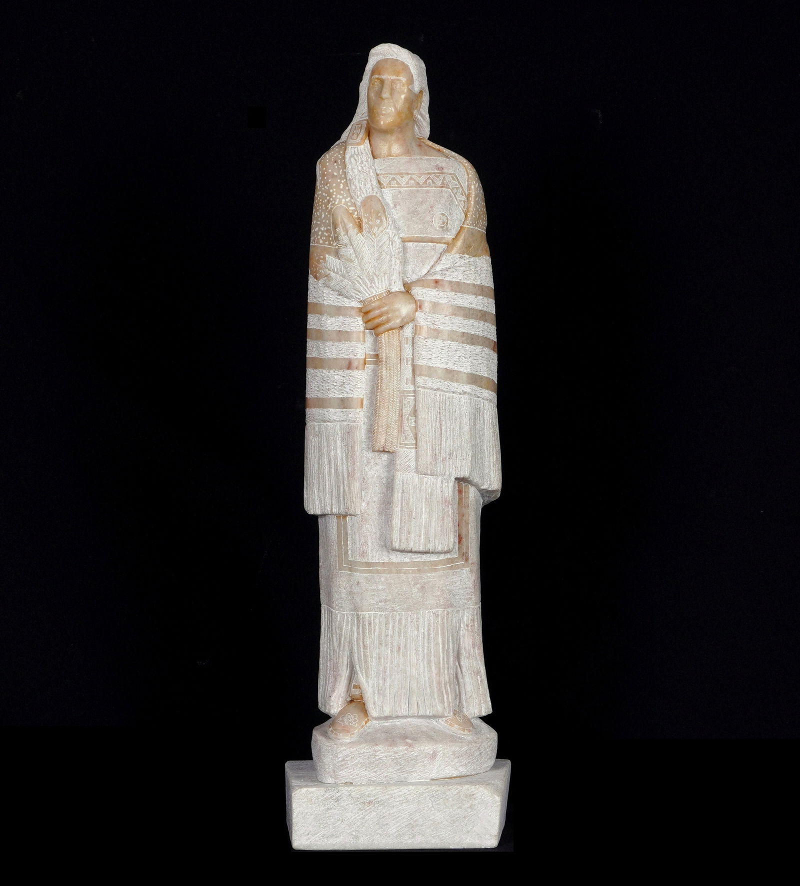 Oreland Joe Carved Alabaster Native American Chief: JOE, Oreland, (Native American, b. 1958): Carved alabaster figure of a Southwest Native American chief wrapped in blanket, holding two feathers, monogram signature at base, overall 15.25" h. x 4.5" x