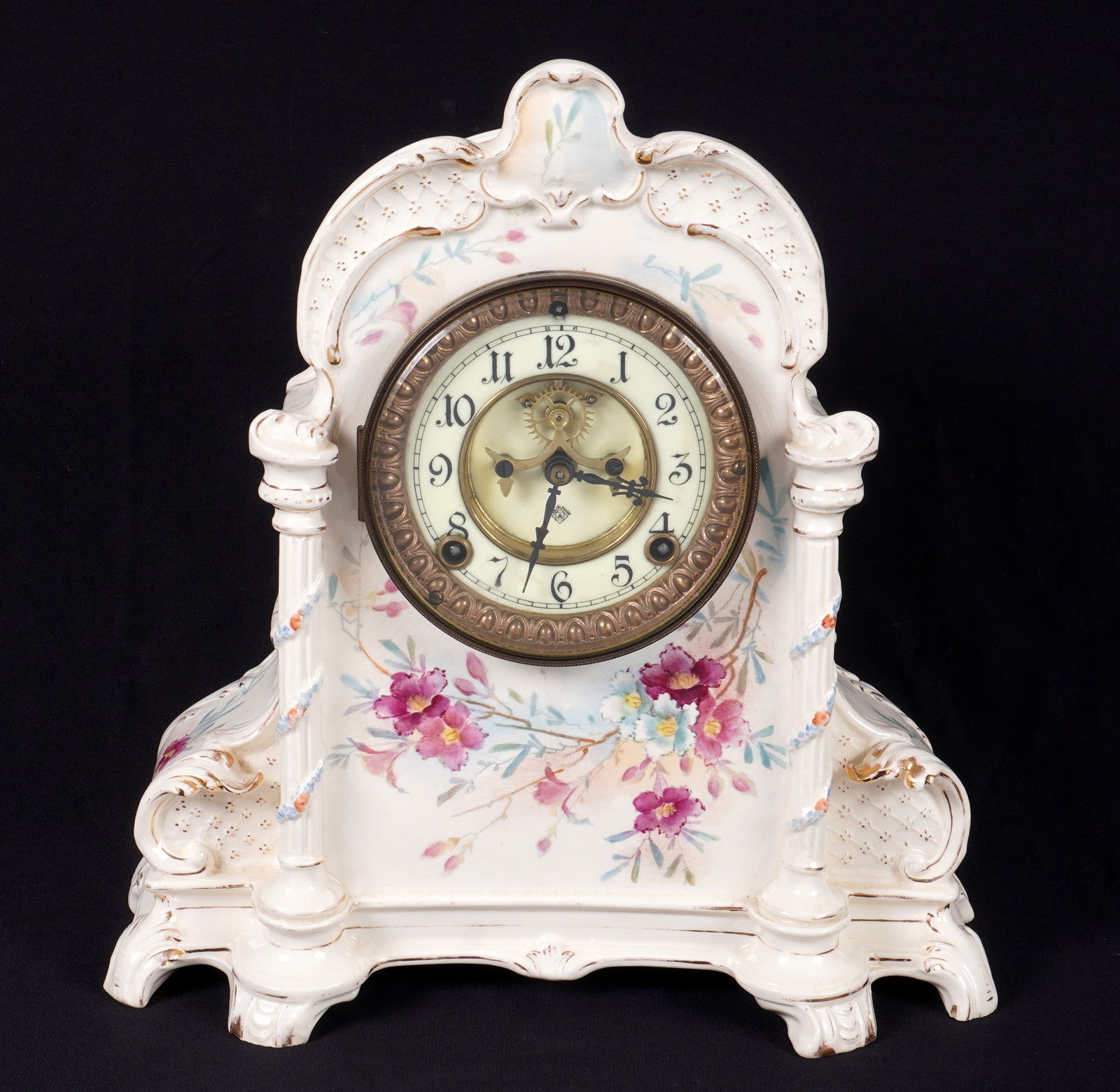 Royal Bonn Ansonia Porcelain Mantel Clock: Royal Bonn porcelain mantel clock, hand painted floral decoration and gilt accents. Enamel dial with open escapement, marked Ansonia. Ansonia time and gong strike movement. Overall 13" h. x 12" x 5".