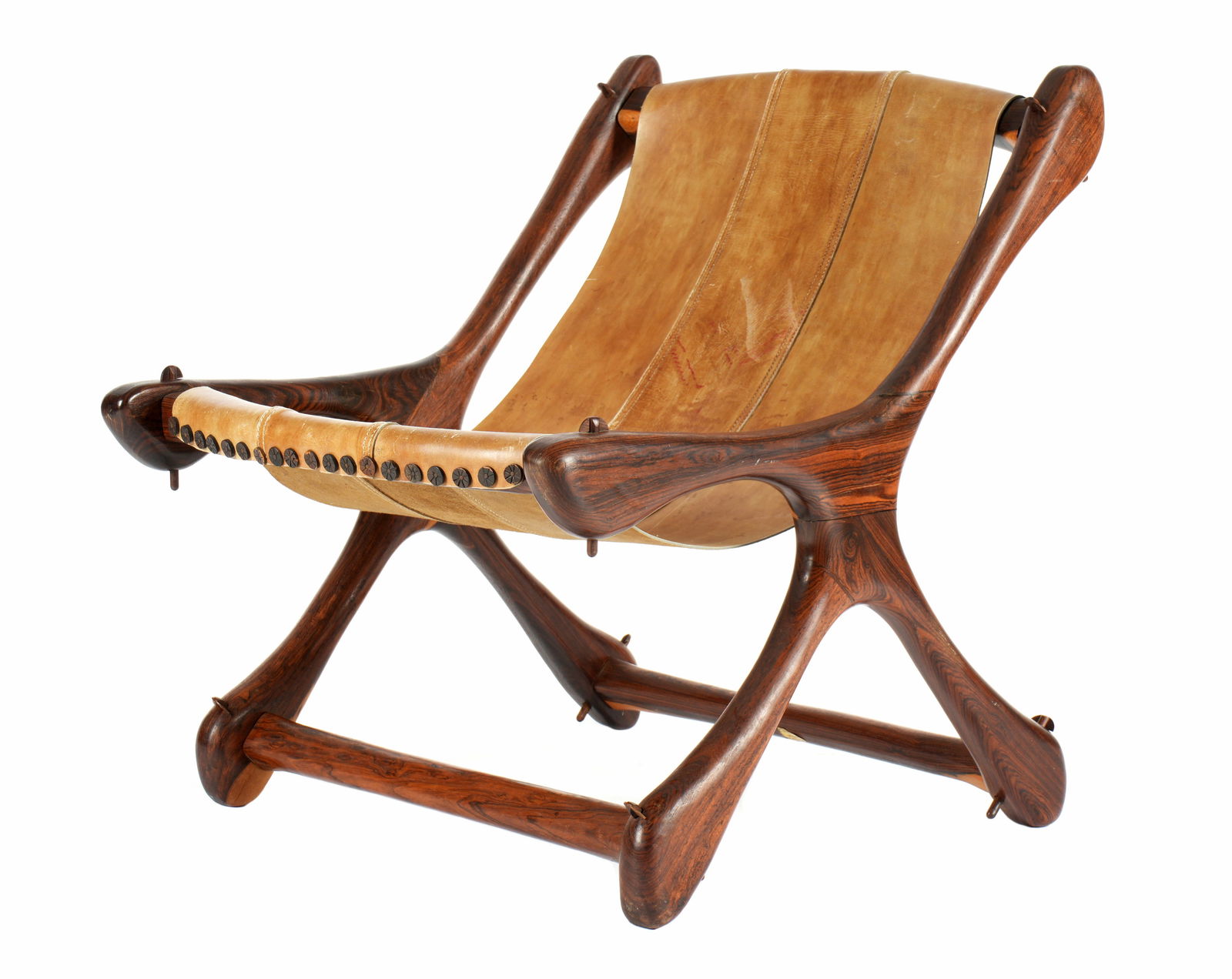 Don Shoemaker Cocobolo Leather Sloucher Chair: "Sloucher' lounge chair by Don Shoemaker, cocobolo wood frame, tan leather seat, partial label. Overall 27.25" h. x 23.5" x 27.25". Condition: Stains to leather, missing two rosettes at top tacks.