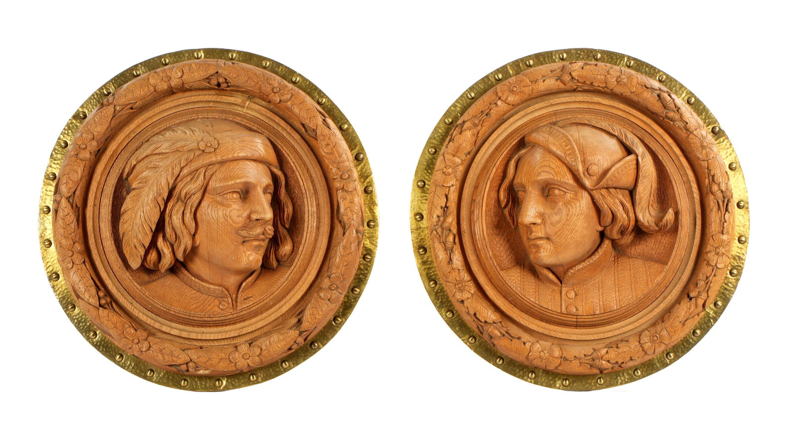 Pair Black Forest Carved Wood Portrait Plaques: One plaque depicting carved oak portrait bust of a man, the other of a woman, foliate and floral outer band, hammered and tacked brass frames. Overall 18.5" dia. x 3.5" deep.