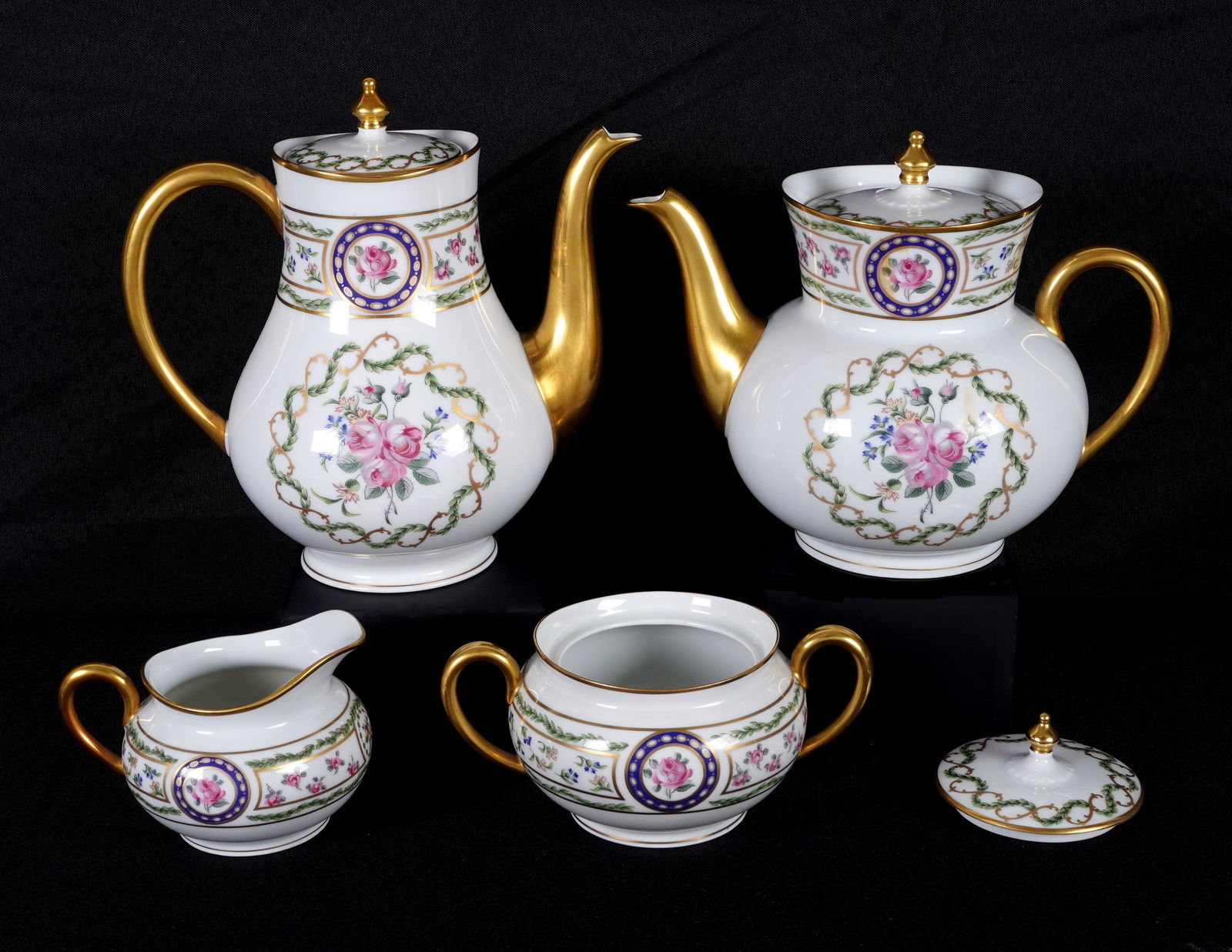 Haviland Limoge Four Piece Porcelain Tea Service: Four pieces total in the Louveciennes pattern by Haviland to include 1) Lidded teapot, 8" h .x 8.5". 2) Lidded coffee pot, 7" h. x 9". 3) Lidded double handle sugar, 3" h. x 6.5". 4) Open creamer, 3"