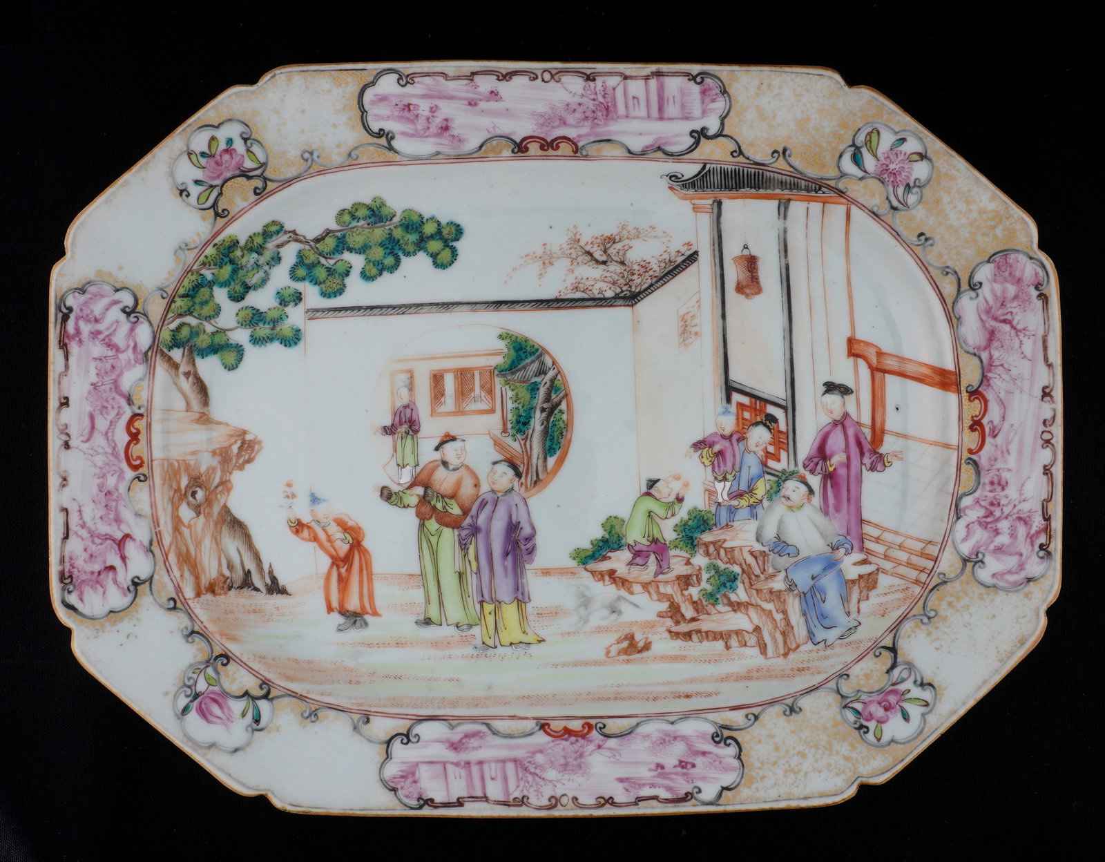 Chinese Mandarin Rose Octagonal Serving Dish: Octagonal porcelain serving dish , center depiction of outdoor terrace genre scene with figures, Famille Rose landscapes in border reserves, unmarked. Overall 13" x 9.75". Condition: Minor wear to dec