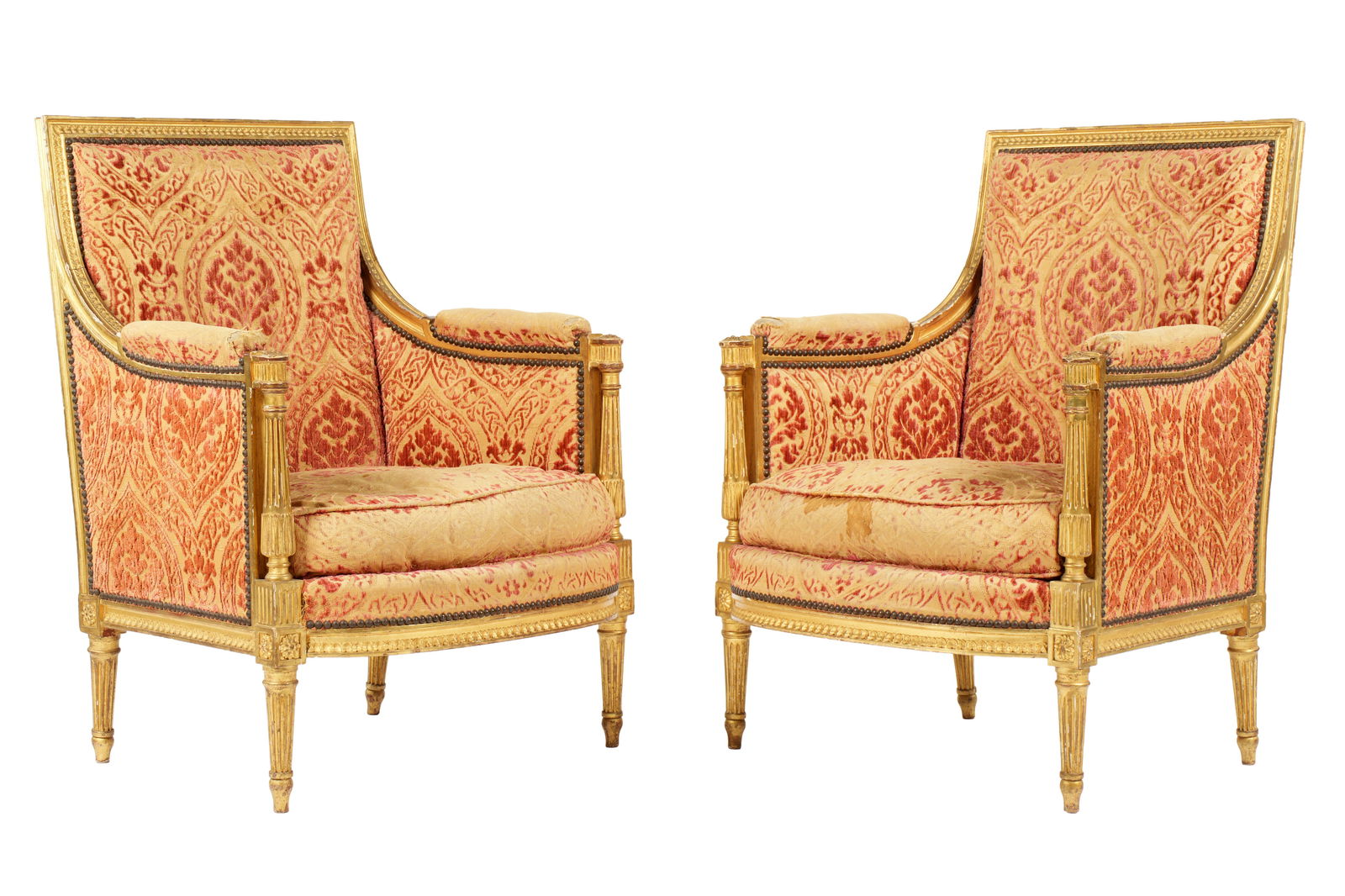 Pr French Louis XVI Carved Giltwood Bergere Chairs: Carved gilt wood frames, turned and fluted columns arm supports continuing to legs, floral medallions at joints. Tacked floral brocade upholstery, overall 37.25" h .x 26.75" x 26". Condition: Chips an