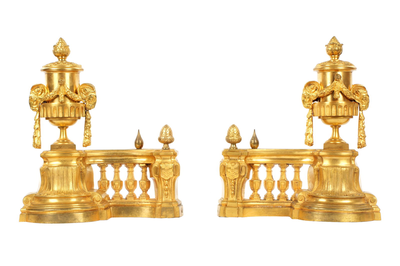 Pair French Louis XVI Style Gilt Bronze Chenets: Pair Louis XVI style, urn form finials with rams heads and garland. Curved column balustrades, overall 14.5" x 12.5. Condition: Minor wear to gilt.