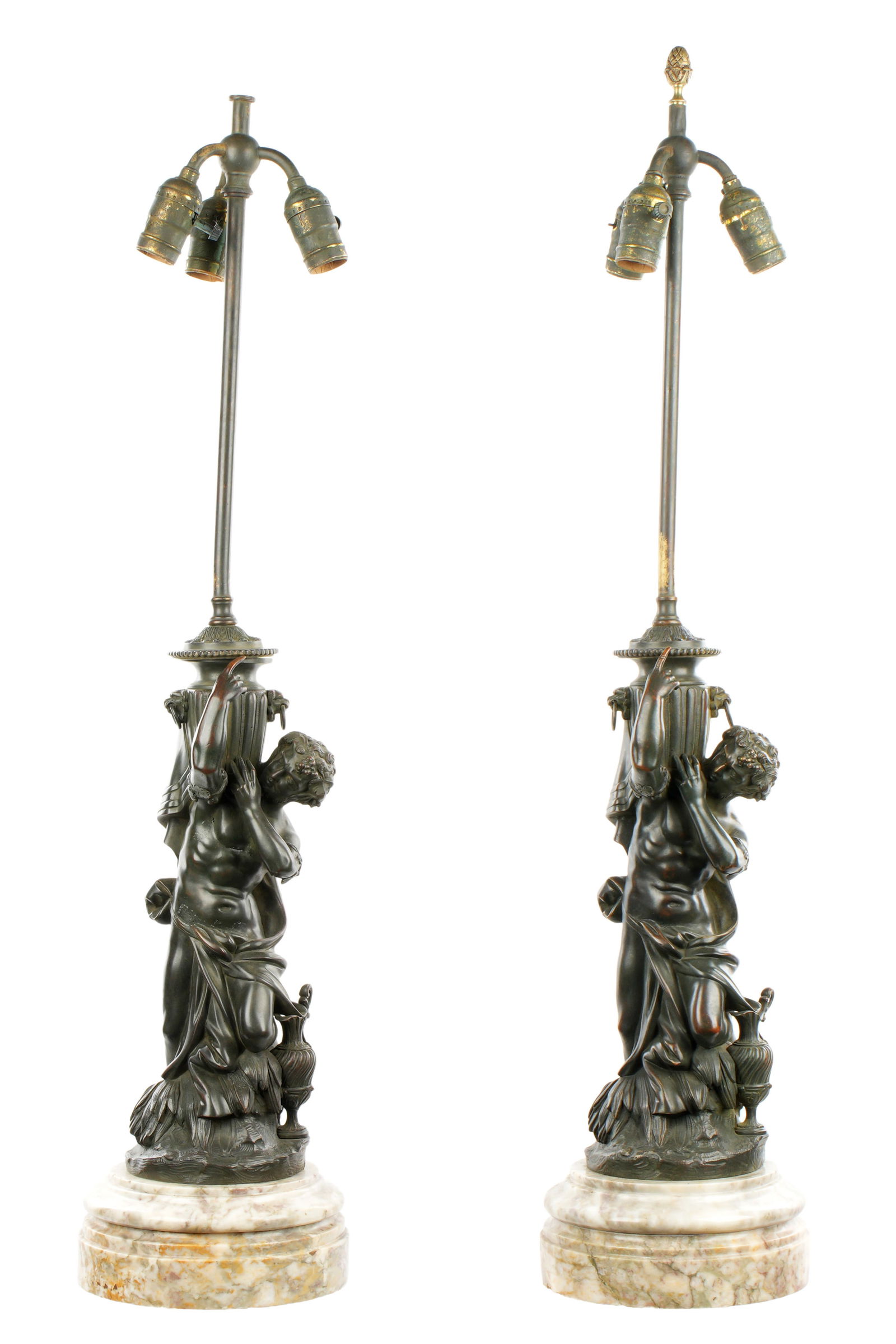 Pair Classical Figure Bronze Lamps: Pair patinated bronze classical male figures holding urns, affixed to round marble bases. Triple socket fixture, overall 36" h. x 7.5". Condition: Uneven patina, one missing finial.