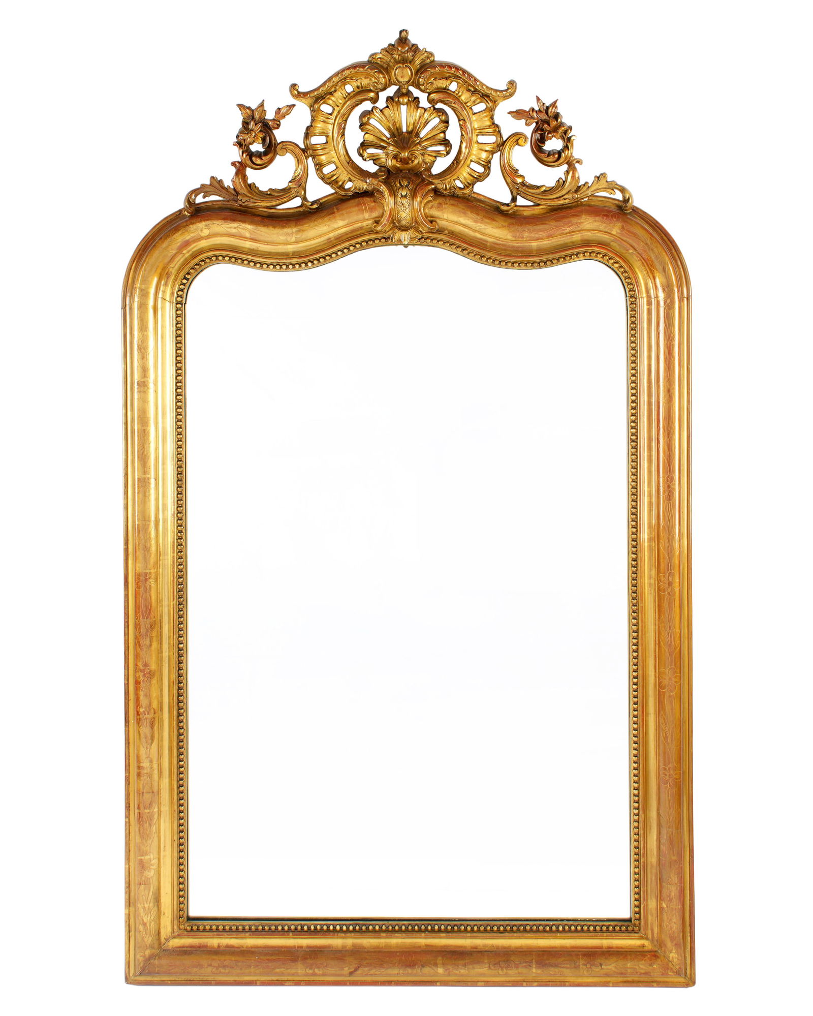French Louis Philippe Carved Giltwood Mirror: Reticulated foliate scroll and shell crest over serpentine top. Frame with lightly carved floral decoration, overall 62.5" h. x 37.75" x 4". Condition: Uneven wear to gilt.