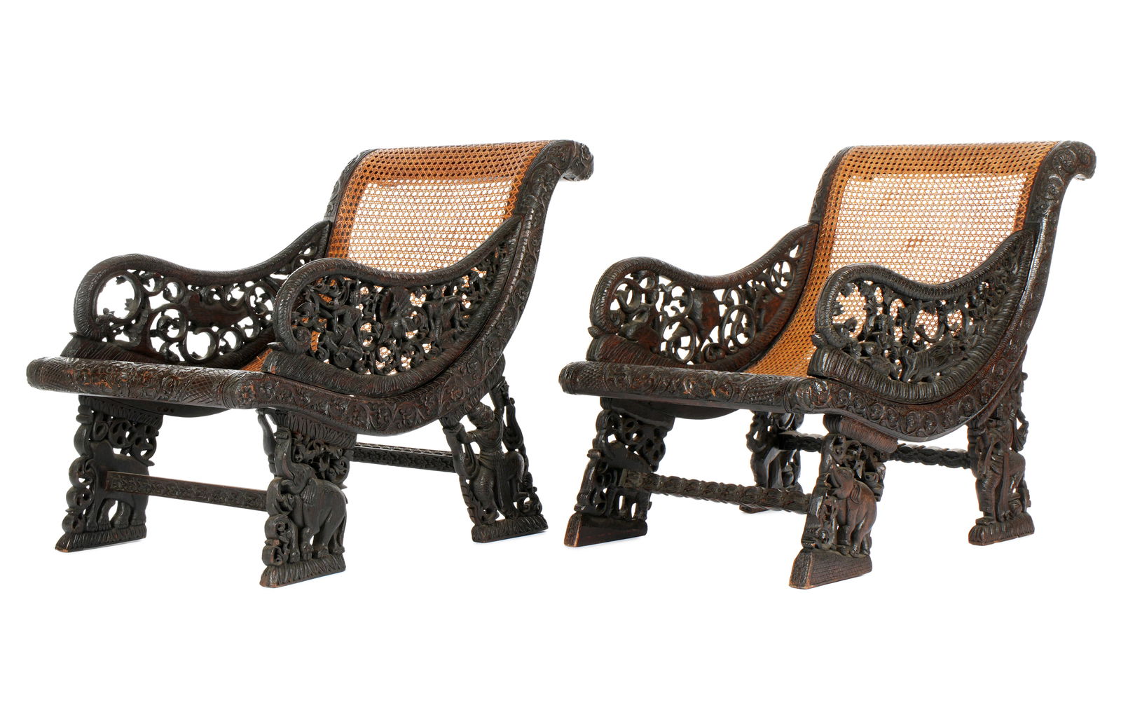 Pair Carved Anglo Indian Woven Seat Chairs: Pair 19th Century, carved wood frames, removable reticulated pierced carved arms with figures, peacock, foliate scroll designs. Reticulated legs with figures and elephants. Continuous woven seat and