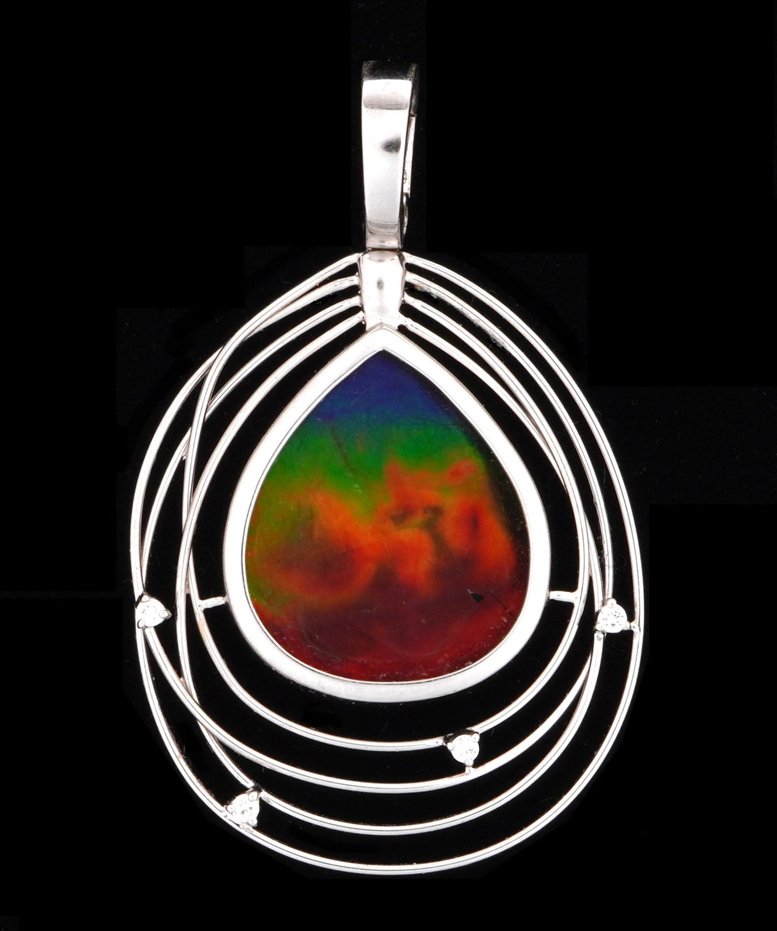 18k White Gold and Ammolite Pendant: 18k white gold frame, center pear shaped ammolite, 20mm x 15mm, four tiny prong set accent diamonds, 35mm x 27mm excluding finding. Approx. 7 grams inclusive. Condition: Internal cracks.