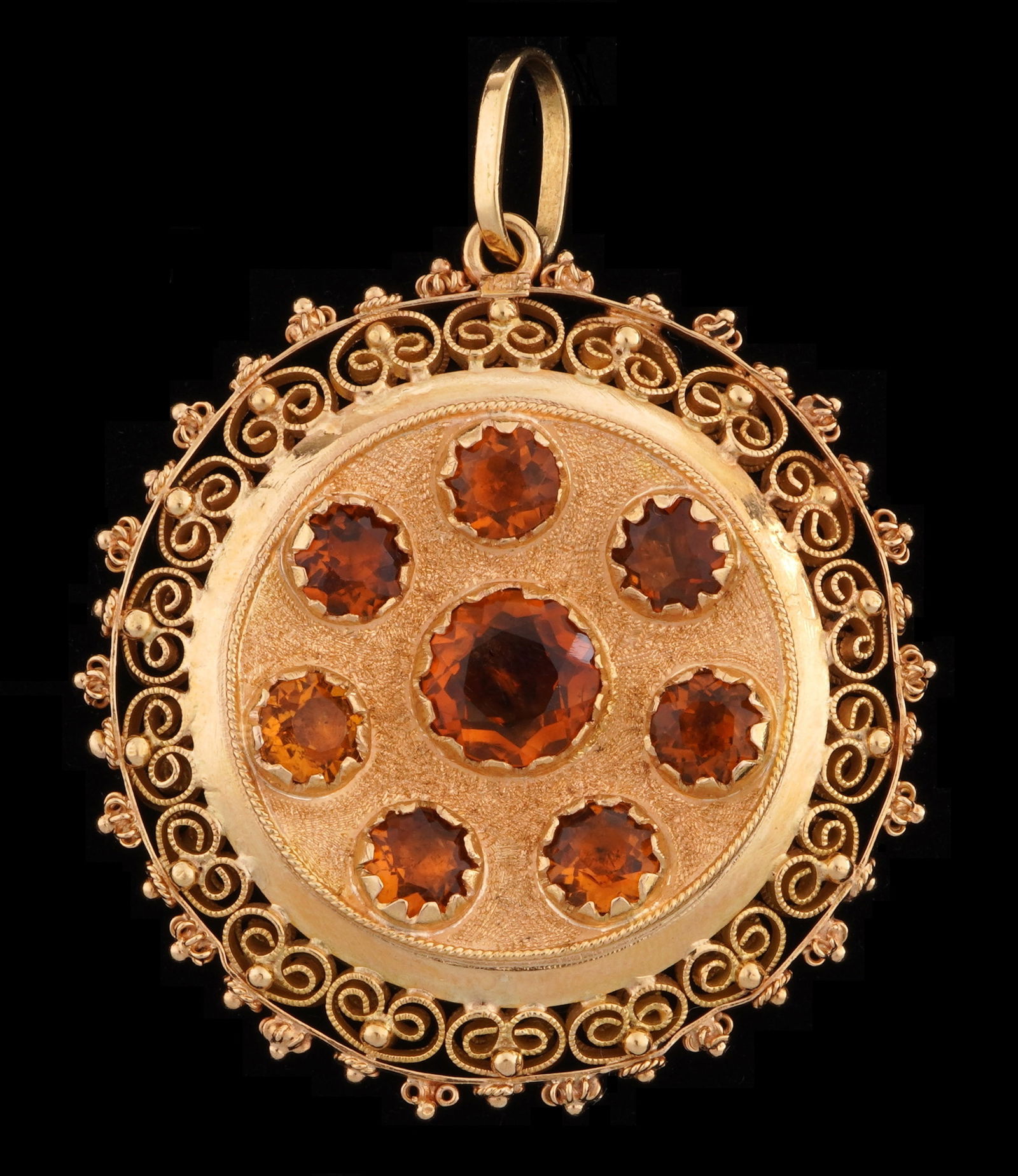 18k Rose Gold and Iolite Filigree Pendant: 18k rose gold frame with filigree border, 16 prong set iolite stones. Pendant bears continental assay mark & 18k. 30mm dia., approx 18.2 grams inclusive. Condition: Small indent at bottom edge.