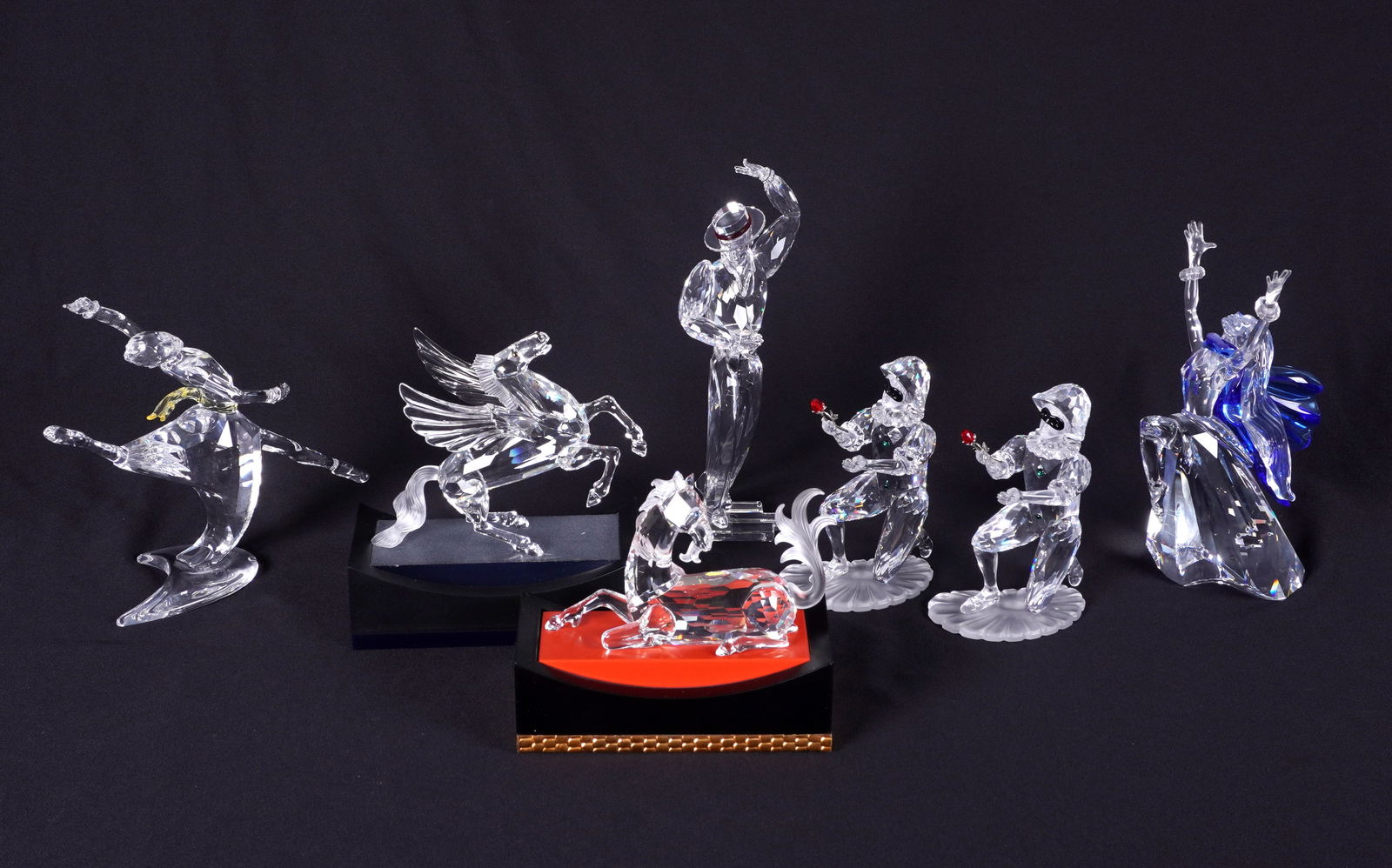 Seven Swarovzki Crystal Figurines with Boxes: An assembled collection of seven pieces total, six with original boxes, to include 2 "Masquerade" Harlequin figures (5.25" h., one missing box), "Magic of Dance" Antonio (8.5" h.), "Magic of Dance" Is