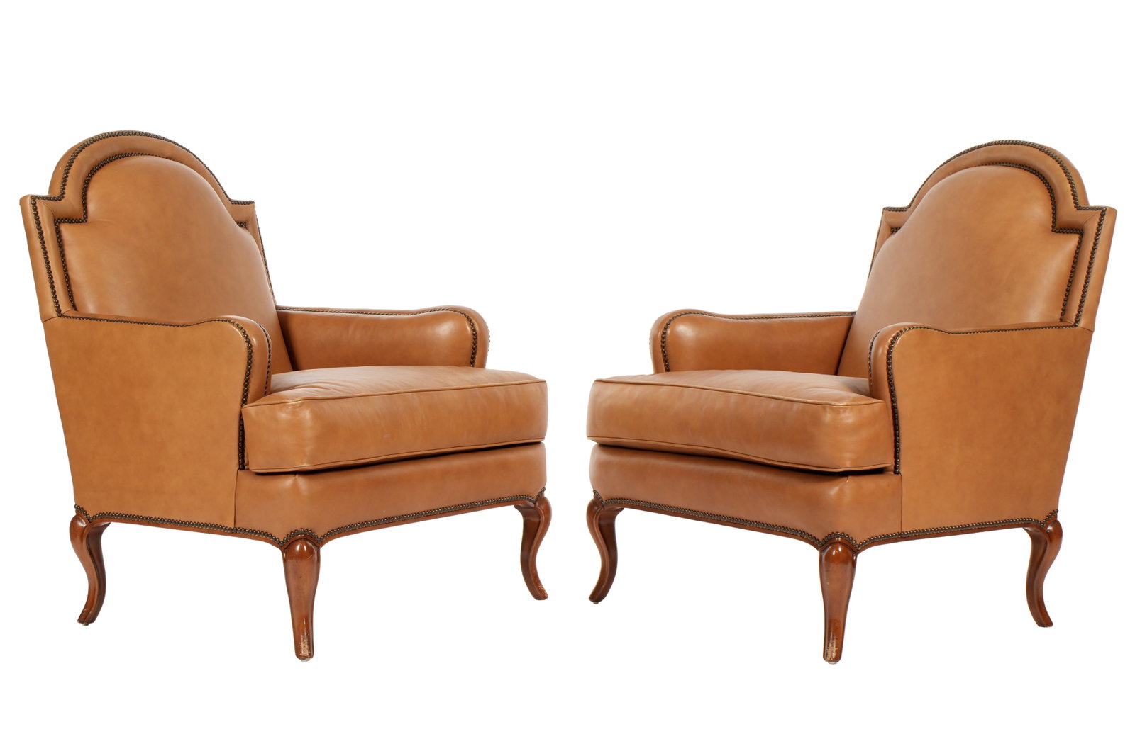 Pair Baker Brown Leather Club Chairs: Arched and shaped tops, tacked brown leather upholstery. Cabriole wood legs. Marked with Baker tags. Overall 39.5" h. x 33" x 33". Seat height 20". Condition: Minor wear to leather.