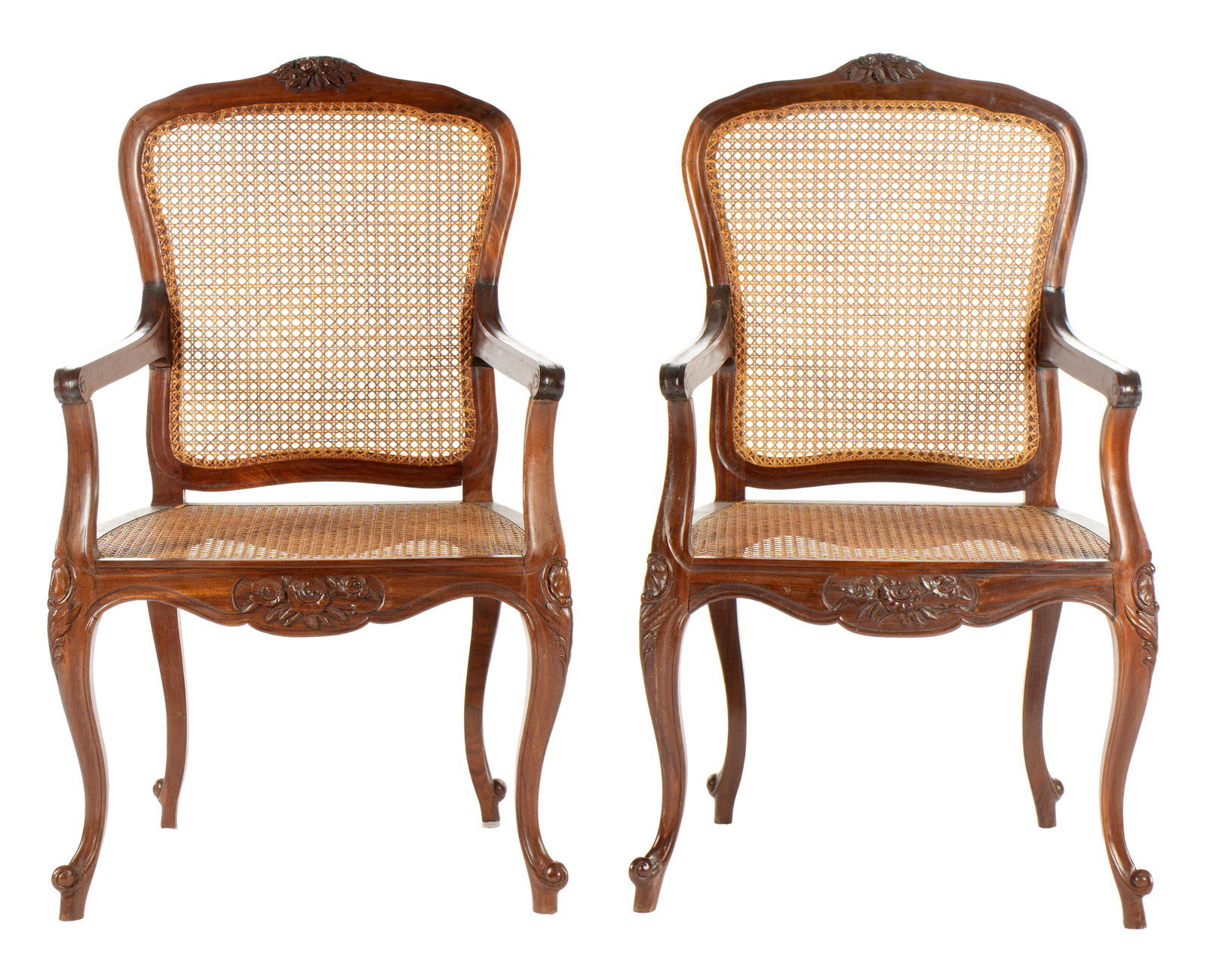Pair French Louis XV Style Caned Fauteuil Chairs: Carved walnut frames, shaped top rail, carved floral crest. Fluted arms, shaped skirt, carved floral medallion. Cabriole legs, caned backs and seats. Overall 42.25" h. x 25" x 20". Wear consistent