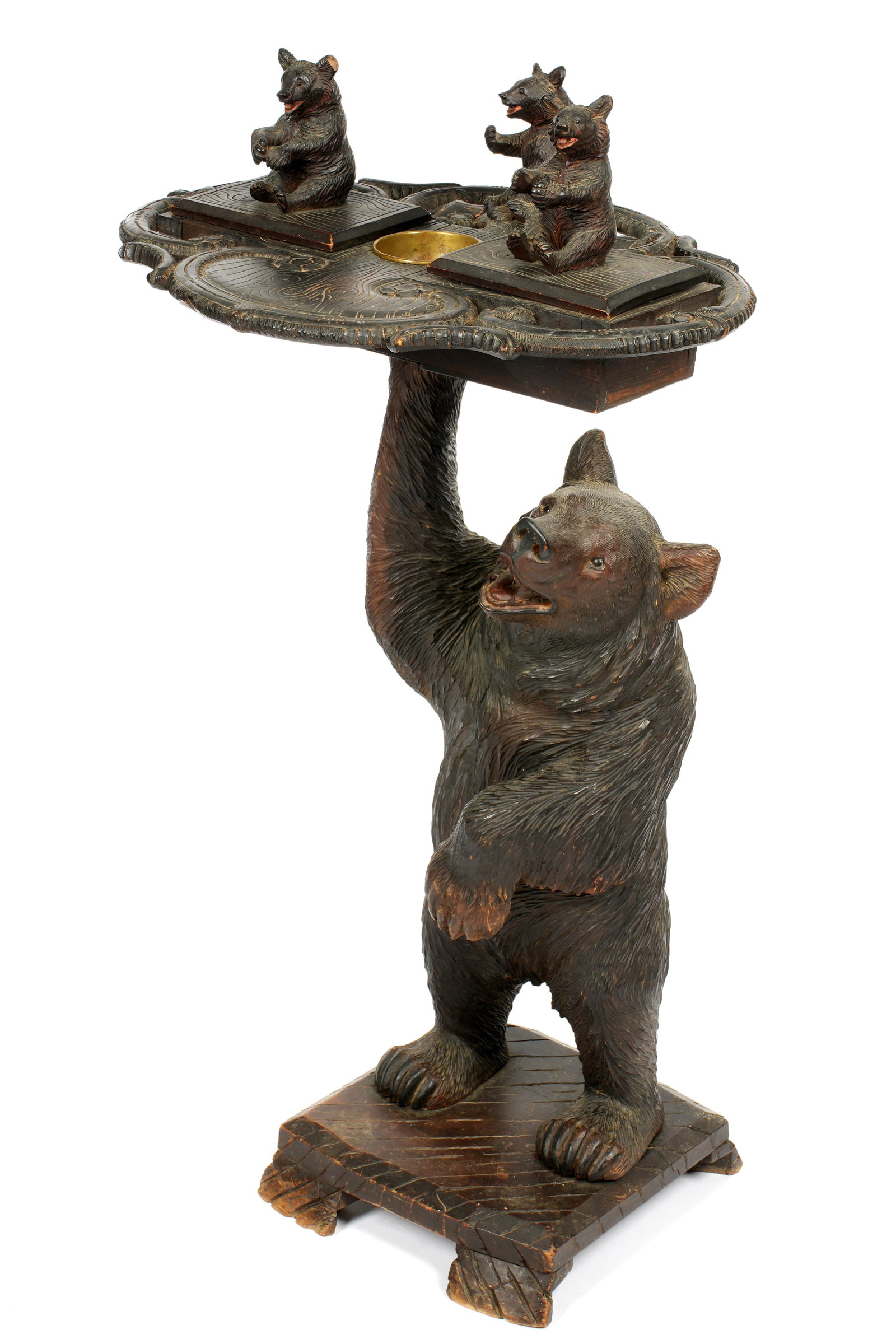 Black Forest Carved Bear Smoking Stand: Carved figure of a bear standing on it's hind legs supporting a tray with two lidded compartments and brass insert ashtray. One compartment with music box operating when opened. Three small bear