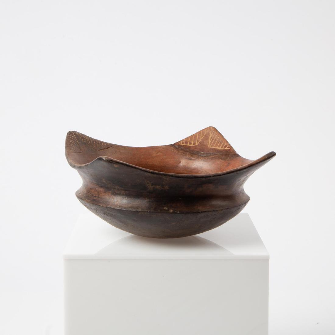 A PRE-COLUMBIAN QUIMBAYA FOUR CORNERED BOWL: Pre-Columbian Quimbaya culture (Colombia, 100 BC - 700 CE). Four cornered pottery cooking bowl, each corner with incised decoration, blackened underside. Measures 4 x 8 x 8 inches.