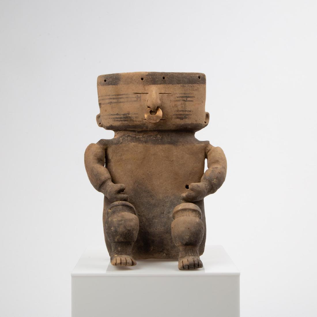 A PRE-COLUMBIAN QUIMBAYA RETABLO SLAB FIGURE: Pre-Colombian Quimbaya culture (Colombia, 100 BC - 700 CE). Seated slab figure with slit eyes and mouth, hands resting on thighs, small gold alloy nose ring. Wide arms suggestive of wide bands. Measur