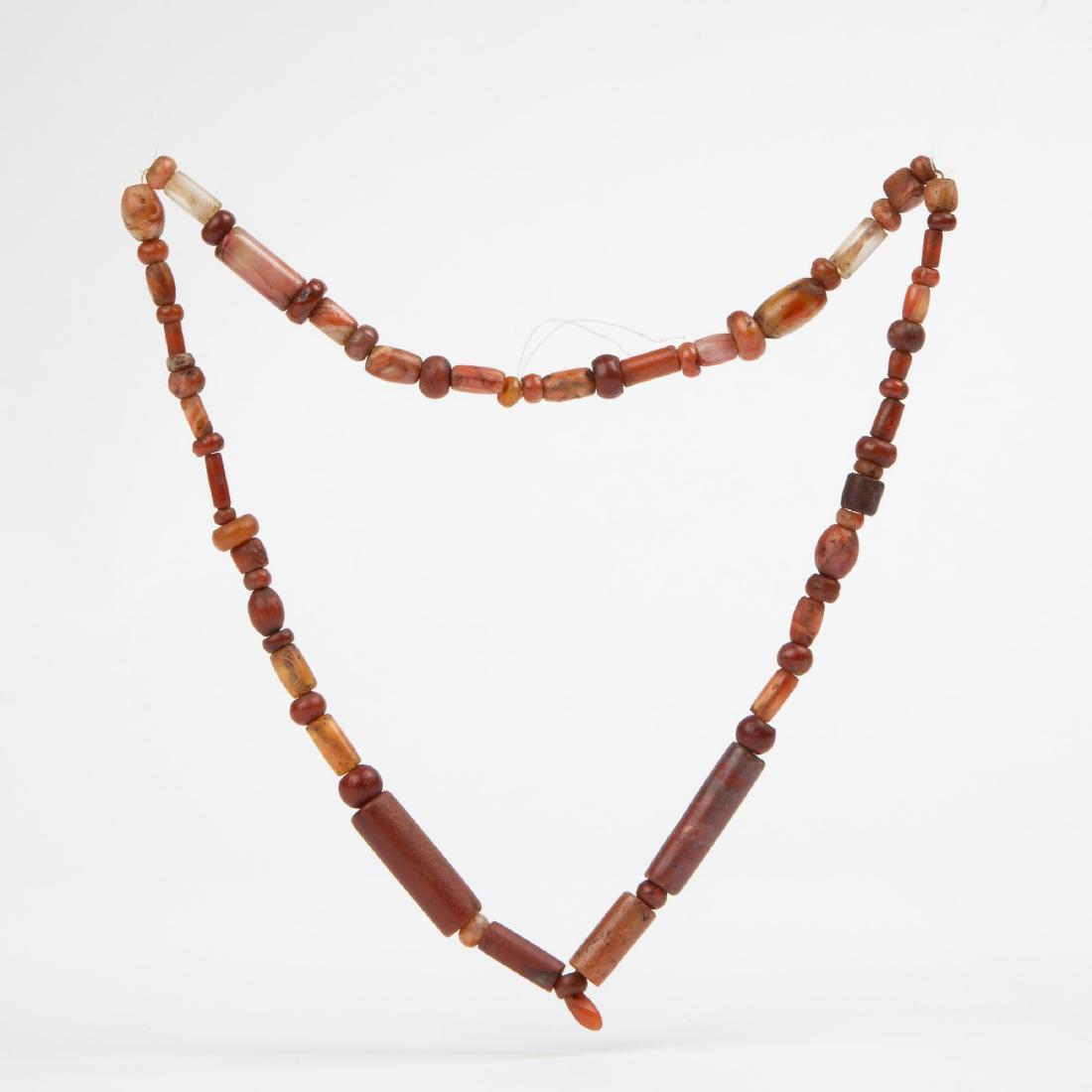 PRE-COLUMBIAN RED JASPER CARNELIAN & QUARTZ: Pre-Columbian red jasper, carnelian and quartz crystal beads. Strung on a knotted clear nylon strand. Center bullet bead is 10 mm long, the largest tube bead measuresÂ 35 mm long and 11 mm toÂ 12 