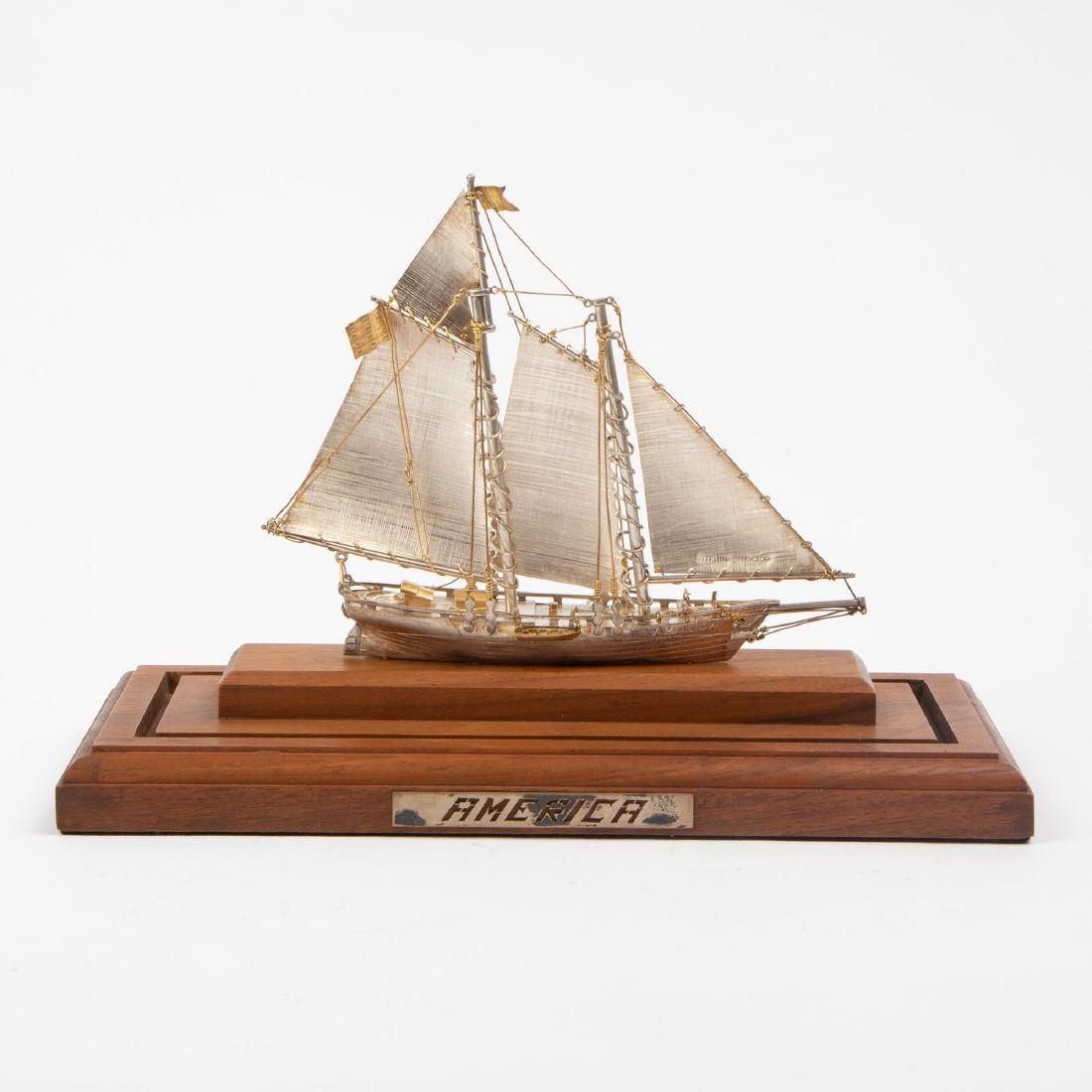 STERLING SILVER MODEL SCHOONER 'AMERICA': A sterling silver model with gold wash detail of the 1851 racing yacht America, the first winner of the international sailing regatta now called the America's Cup. The schooner is affixed to a wooden