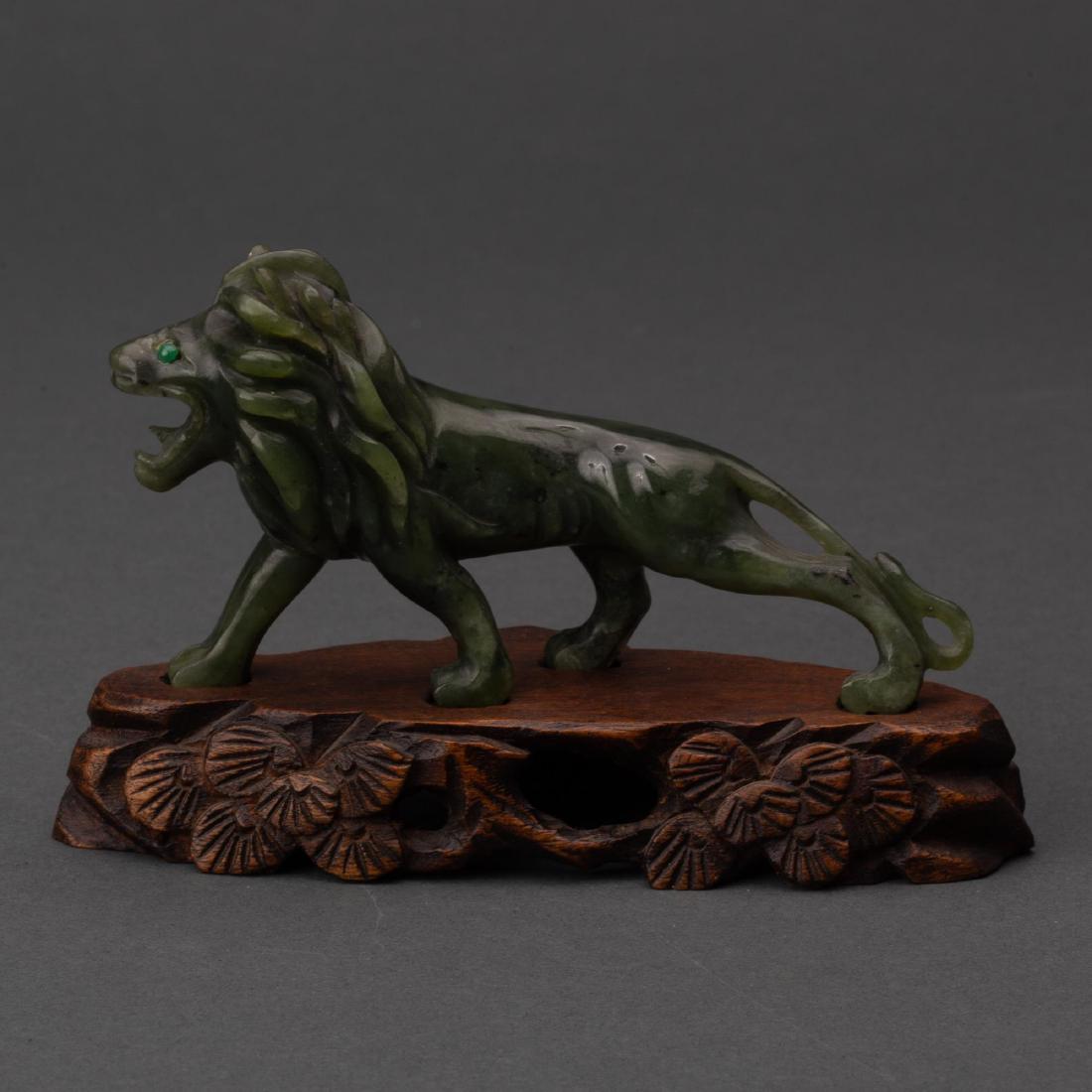 CARVED CHINESE NEPHRITE SPINACH JADE LION WITH EMERALD: Nephrite spinach-colored jade carving of a lion with emerald eyes on stand. Not native to China, the lion was sometimes brought to the Chinese emperor as a tribute and symbolizes protection, harmony, 