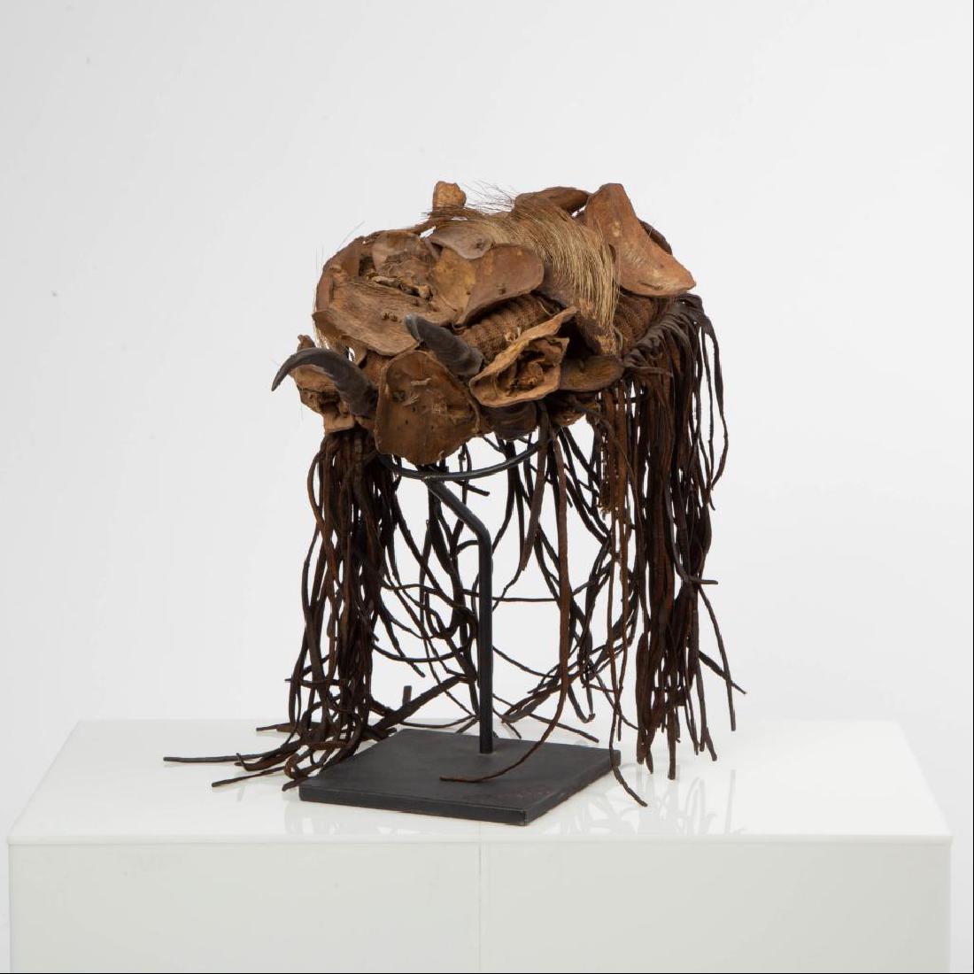 MALI WEST AFRICA TRADITIONAL HUNTER'S HAT: A heavy brown burlap base cap with applied round leather discs, some with original animal hair, plus two small horns applied to the forehead, and leather fringe hair around the sides and back. Small s