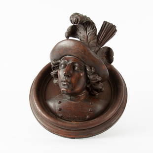 19th c. Black Forest Carved Bust on Medallion: A finely carved 19th century Black Forest walnut and red oak bust of a handsome young man in a plumed cap and military coat. Affixed to a wall-hanging oak medallion. Said to have been