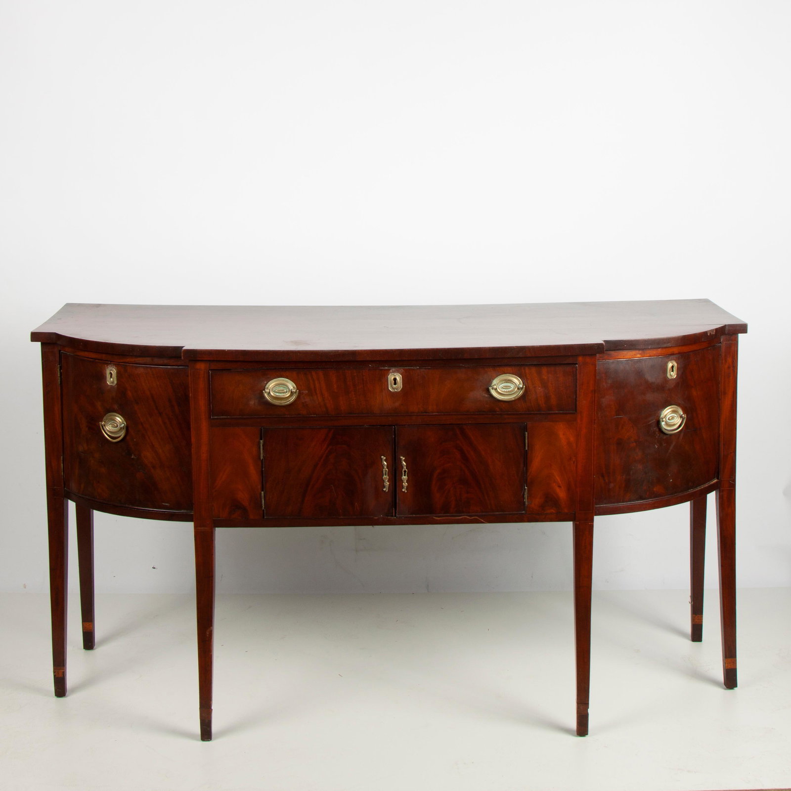 18th c. American Hepplewhite Mahogany Sideboard: An early 18th c. American sideboard in the Hepplewhite style, flame mahogany veneers on oak and pine solids. Subtle string inlays, and early brass hardware. A single drawer above a two-door cabinet, f