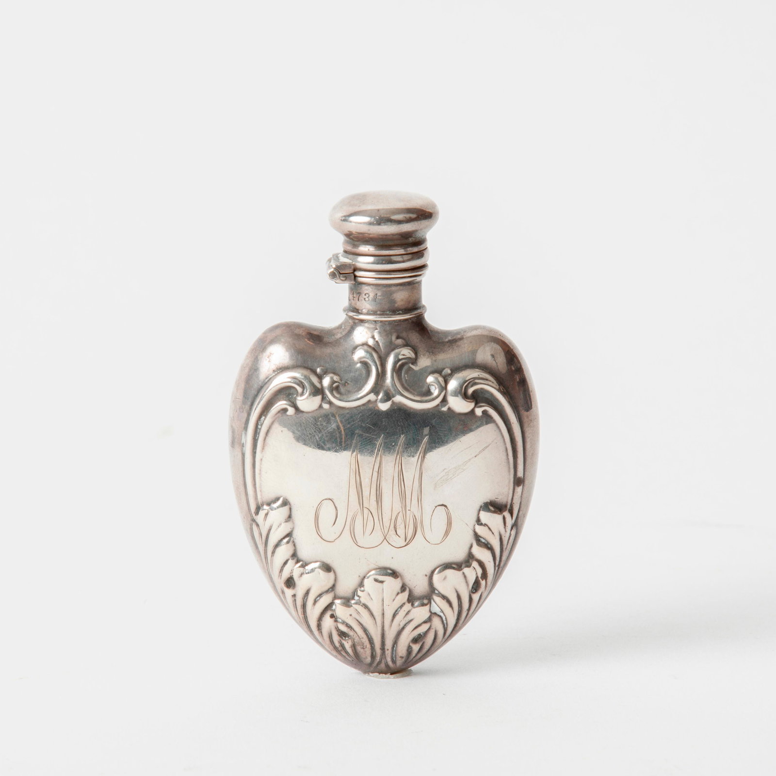 Whiting Sterling Perfume Flask, circa 1895: A Whiting Manufacturing Co. sterling silver heart-shape perfume flask, chased acanthus leaf motif, with "MM" monogram on one side, circa 1895. Locking twist cap. Stamped on the neck with a Whiting pic