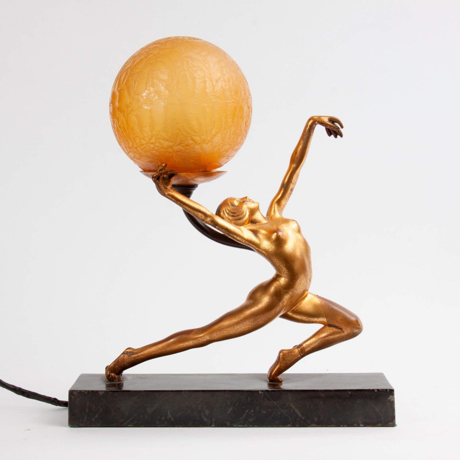 Figural Nude Art Deco Lamp with Crackle Glass Globe: A figural nude Art Deco dancer lamp with gold patina. Topped with a Czech amber crackle glass globe. On a marble-patinated metal base, outfitted with a turning switch. Measures 13 1/4" x 11 1/4" x 4 3