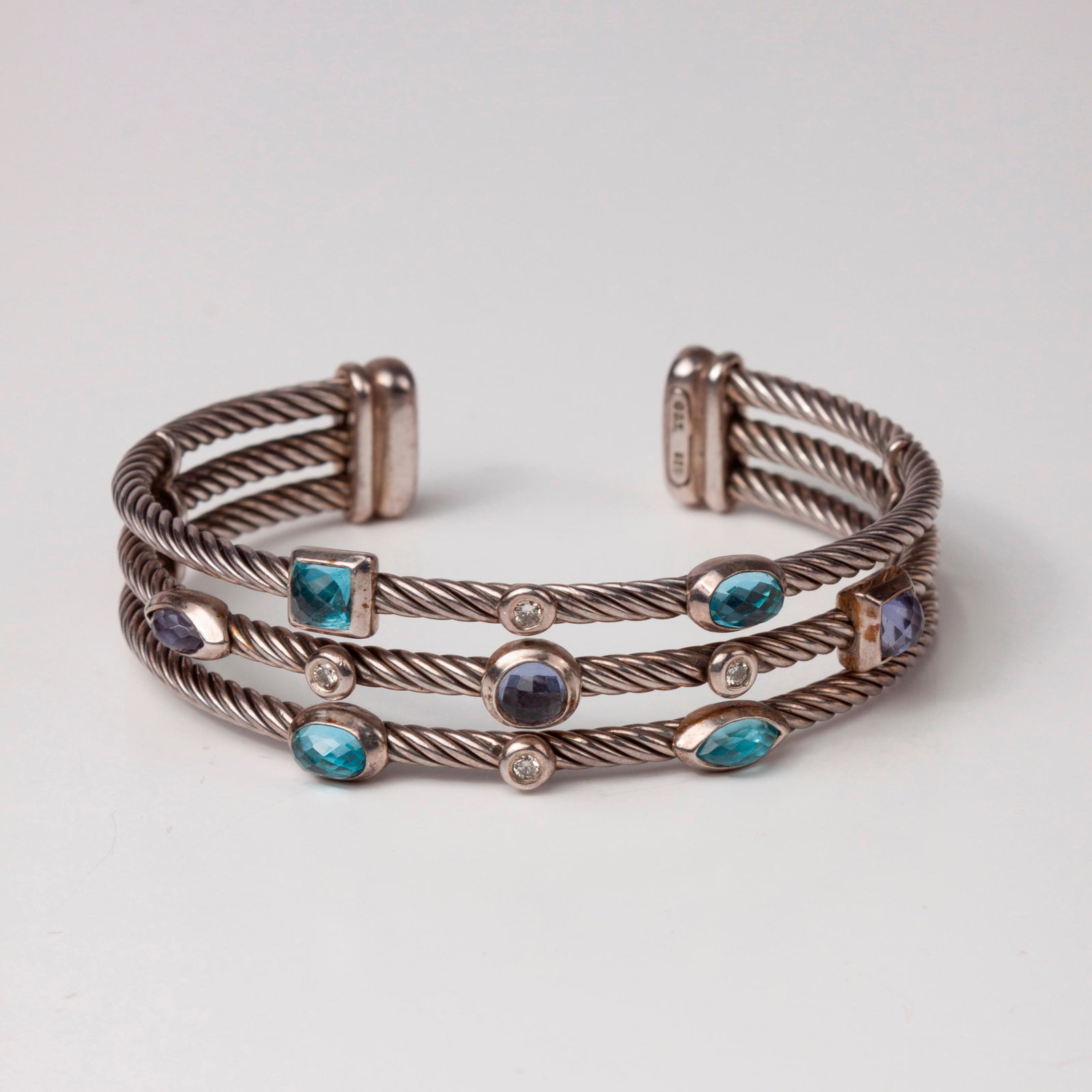 David Yurman Confetti Cuff, w/ Diamond, Topaz, Iolite: David Yurman three row 'Confetti' cuff with iolite, topaz, and diamonds. There are three twisted cable rows each 3 mm in diameter. The center row has three faceted iolite, each bezel set including&nbs