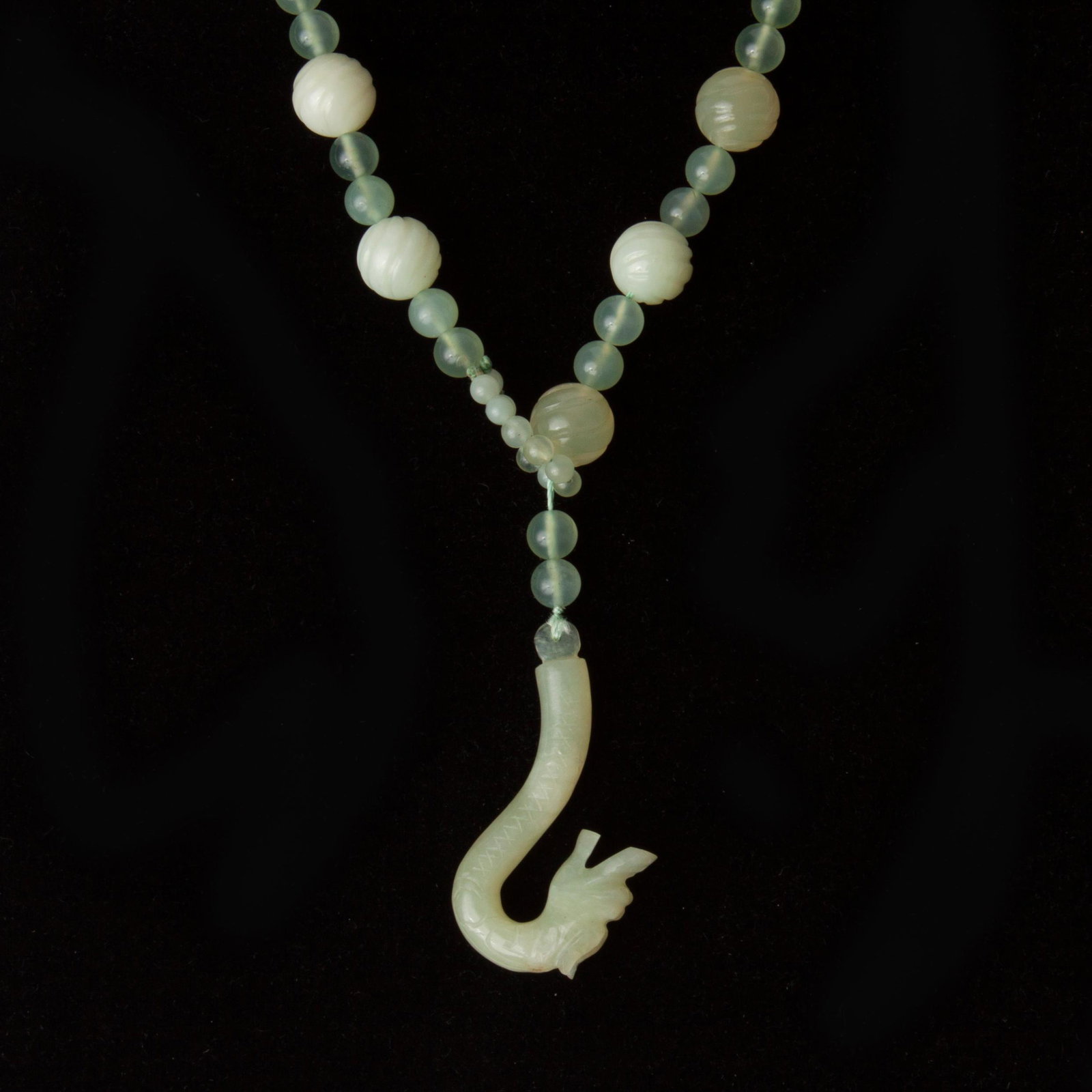 Jadeite Jade Dragon Hook Lariat Necklace: Jadeite jade carved dragon lariat style necklace with icy light green jade carved beads. The beads are 12 mm - 14 mm and are spaced with two smooth 7 mm jadeite beads. The end of t
