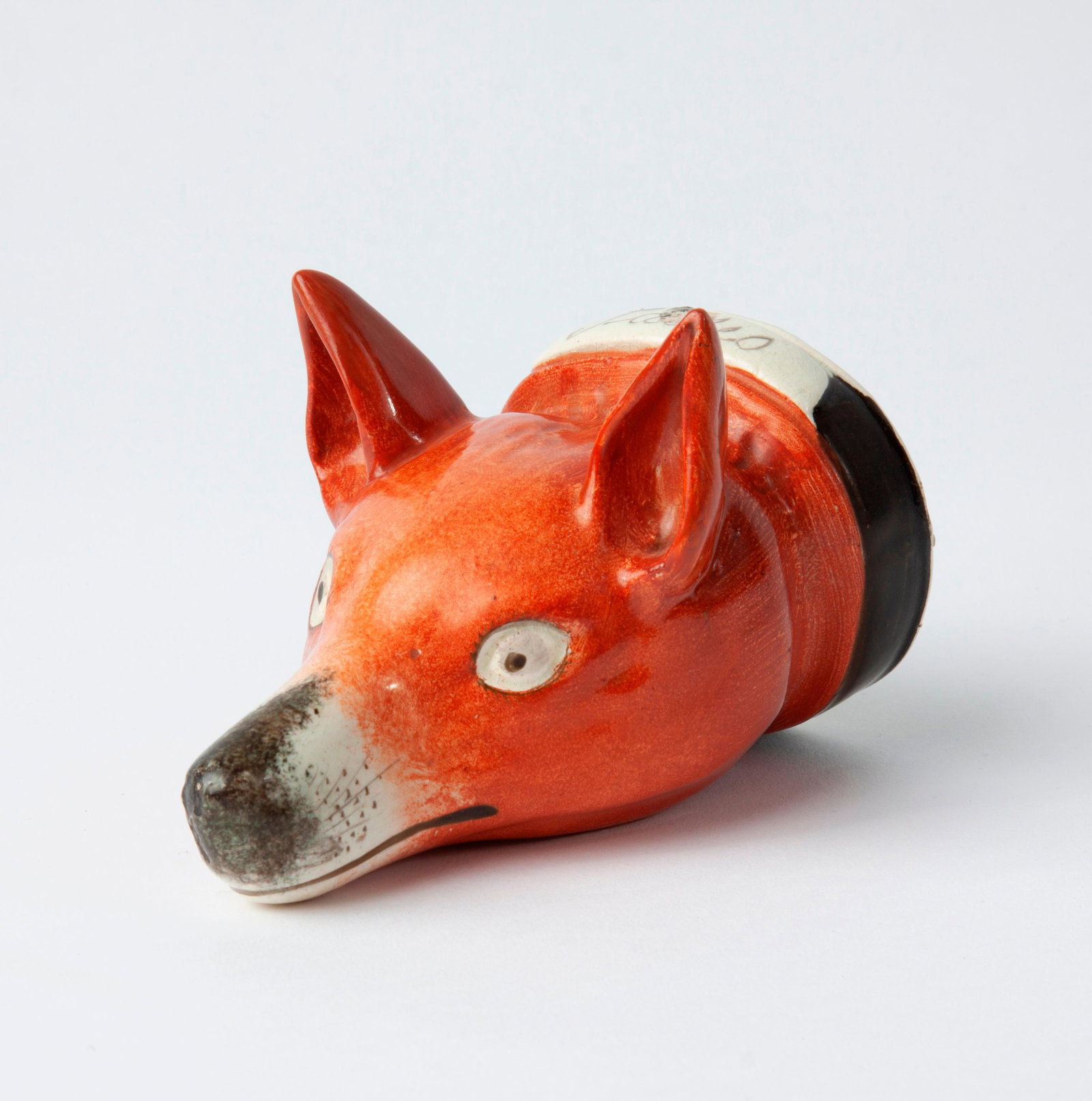 19th c. Staffordshire Pottery Fox Stirrup Cup: A 19th c. Staffordshire painted pottery stirrup cup in the form of a fox head, with a collar that reads "Tallio". Measures approximately 4 3/4" x 3 1/2" x 3 1/4".